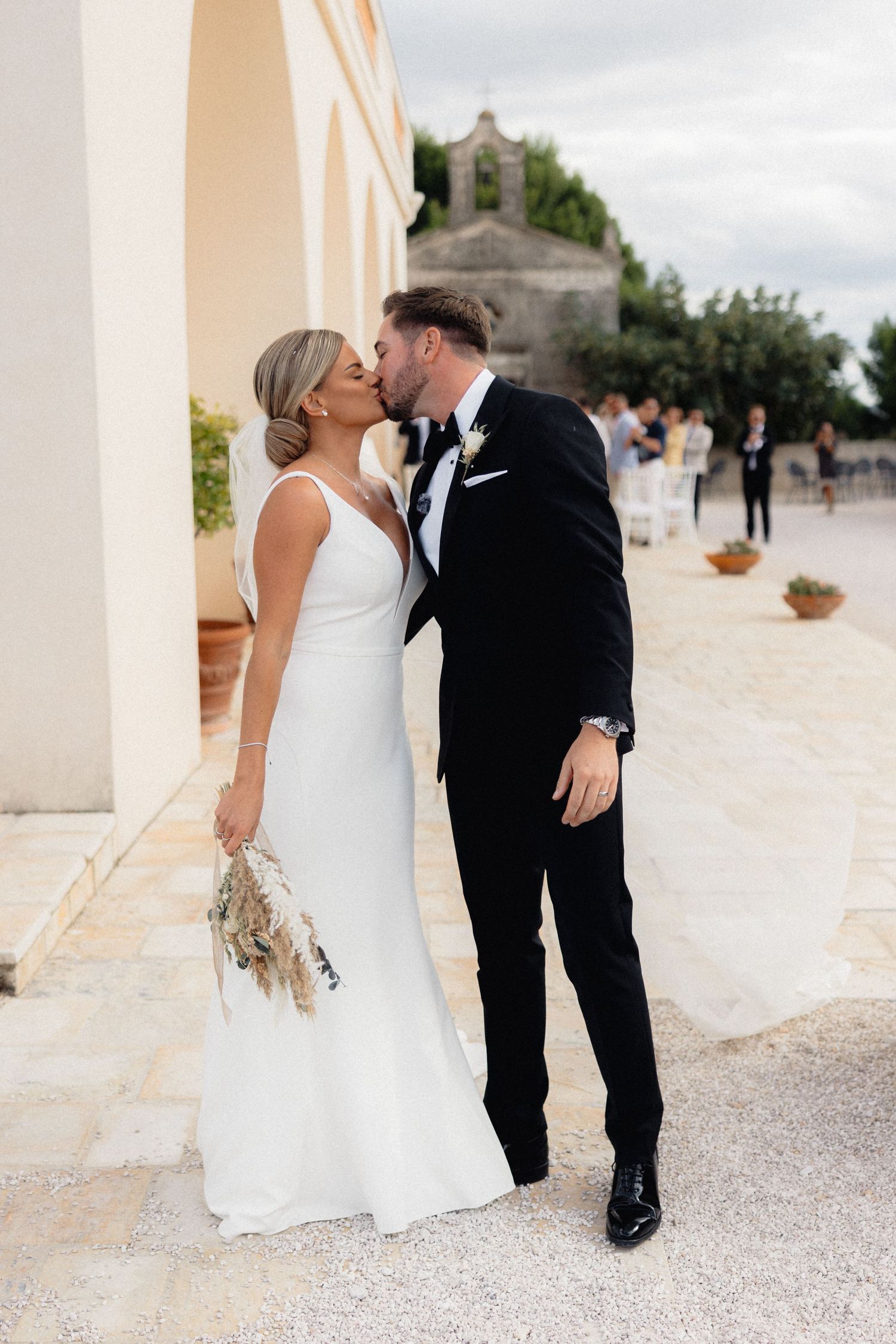 Romantic wedding moments captured on a light stone terrace with church in background.