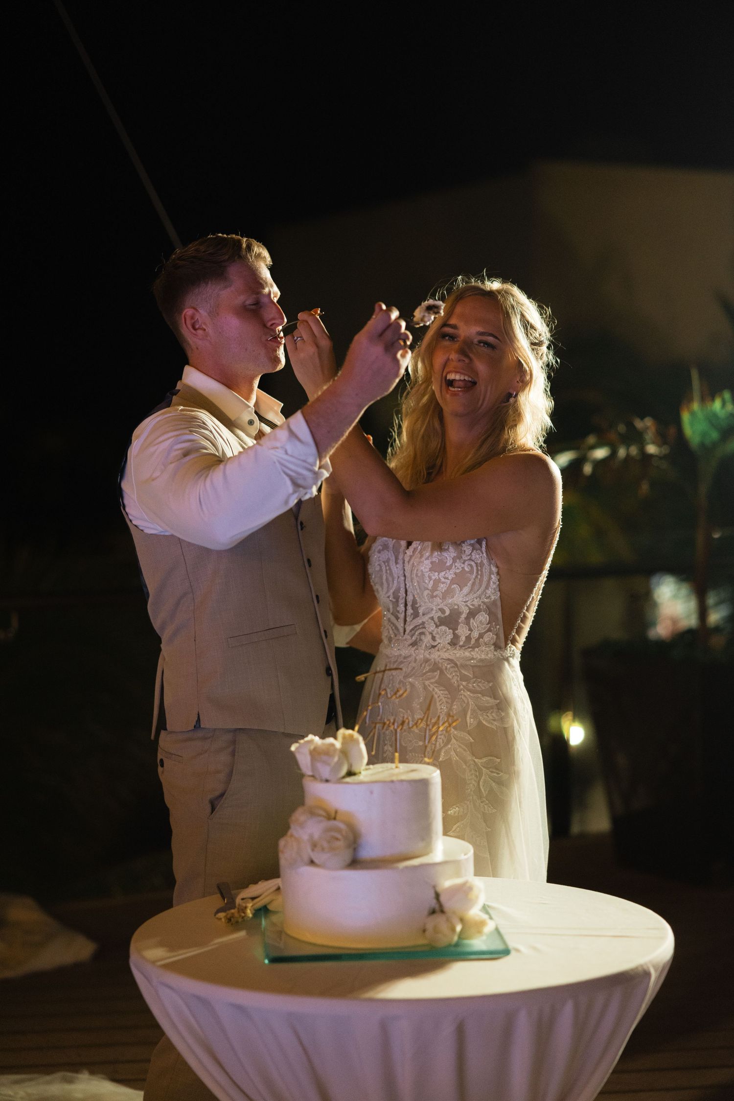 Newlyweds share a playful moment while feeding each other wedding cake during their reception celebration.