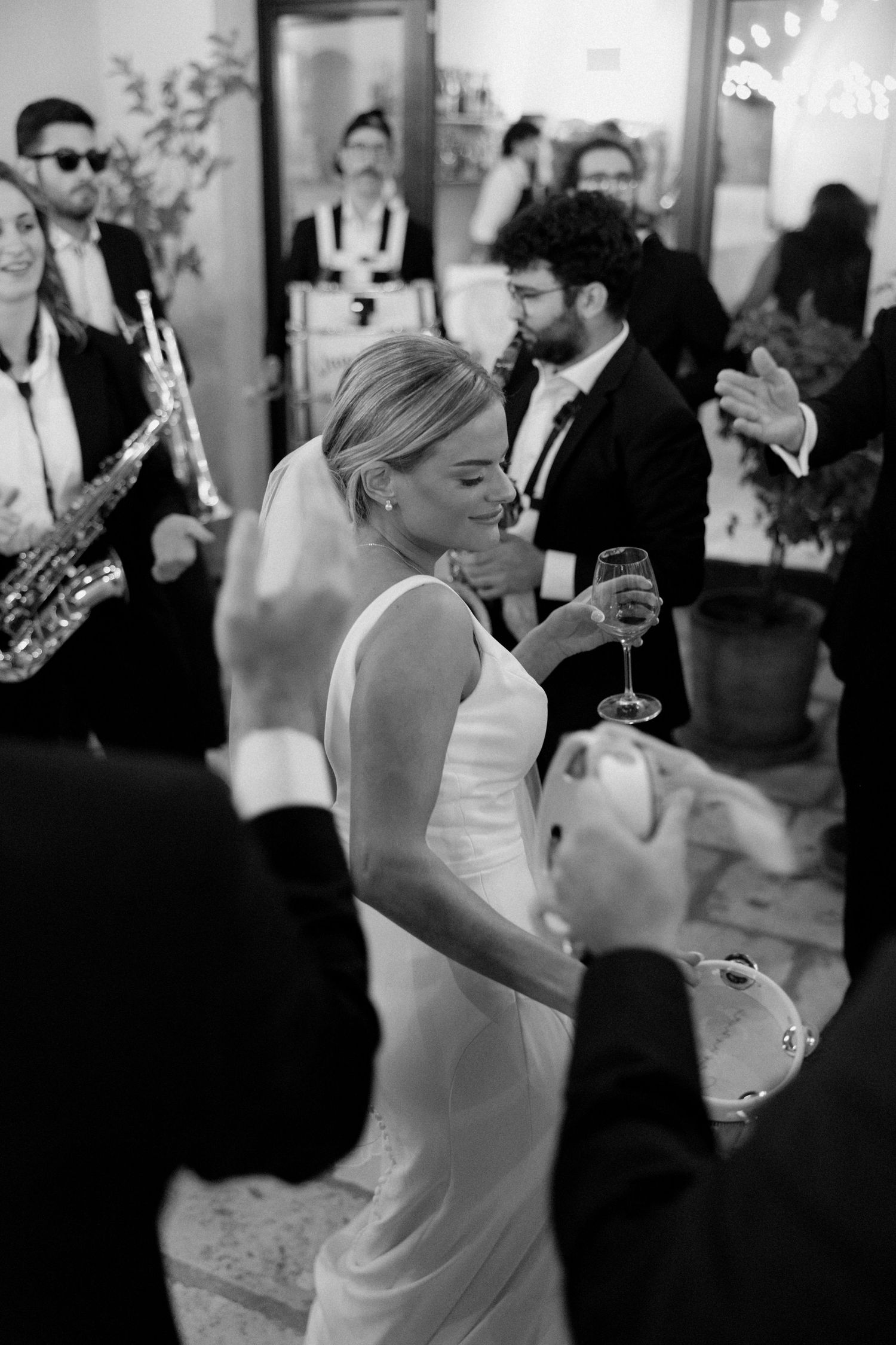 Black and white photo of wedding guests dancing and celebrating at indoor reception.