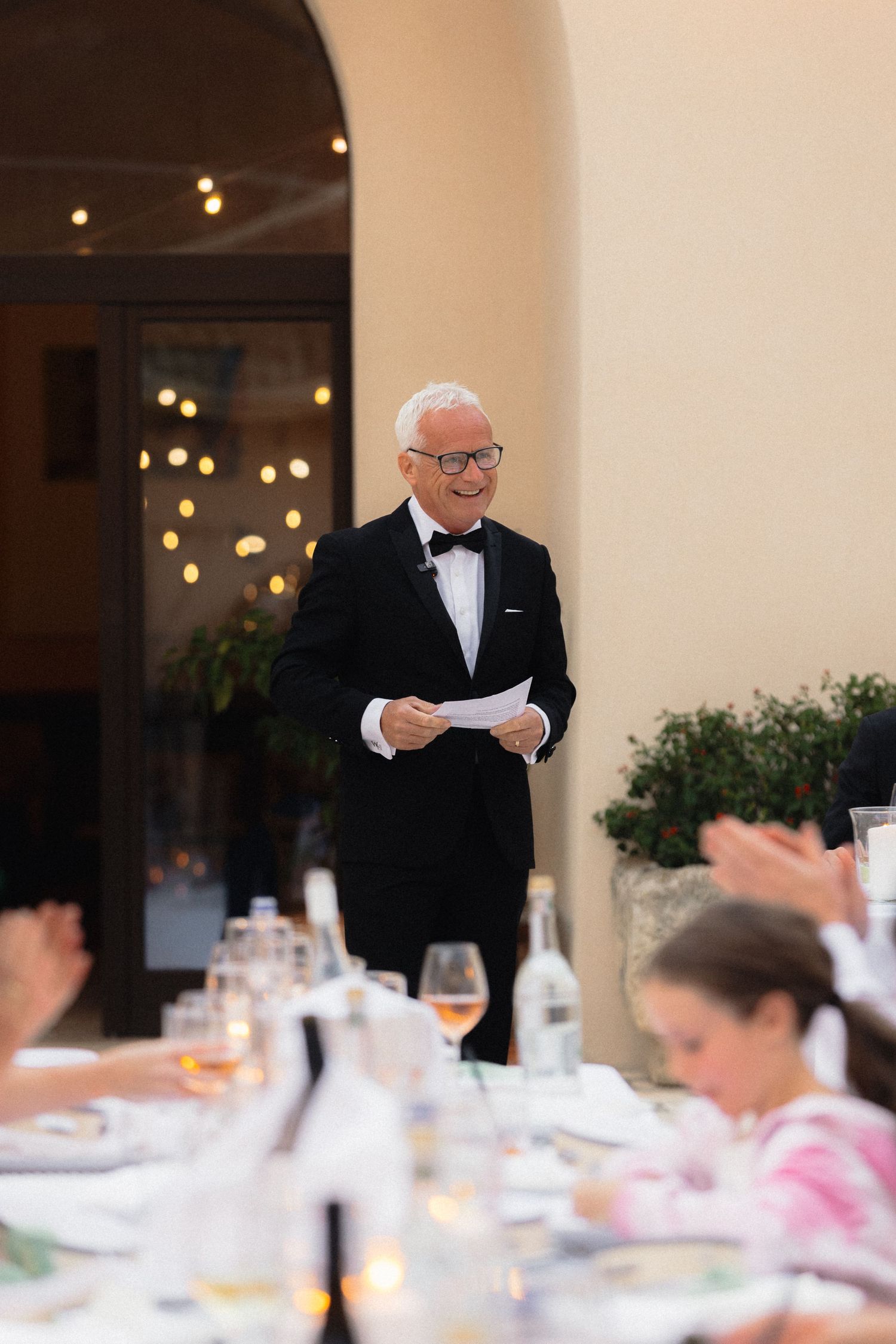Wedding guest in formal attire delivers a heartfelt speech at an elegant reception dinner.