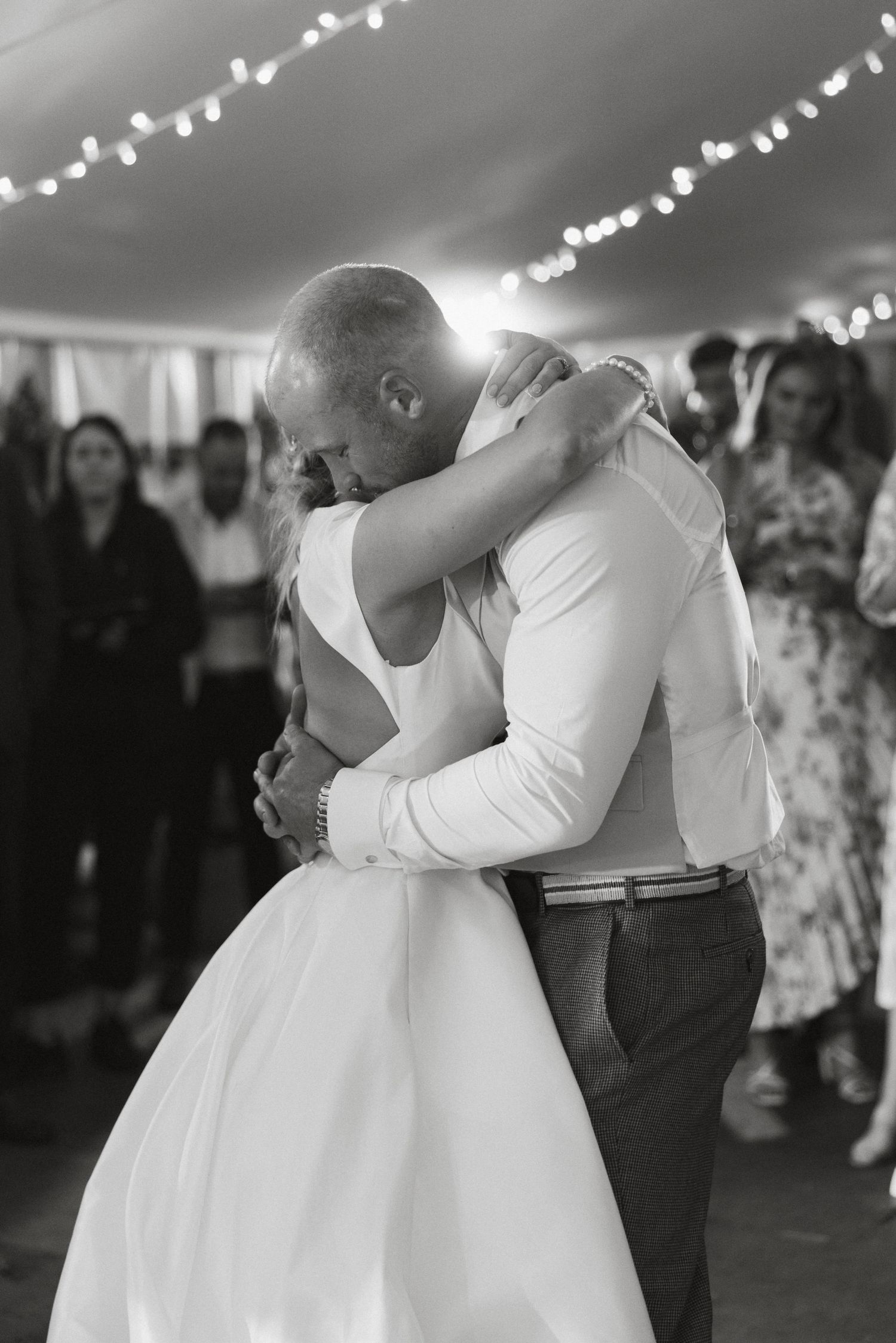 Black and white photo of intimate wedding dance moments under twinkling reception lights.