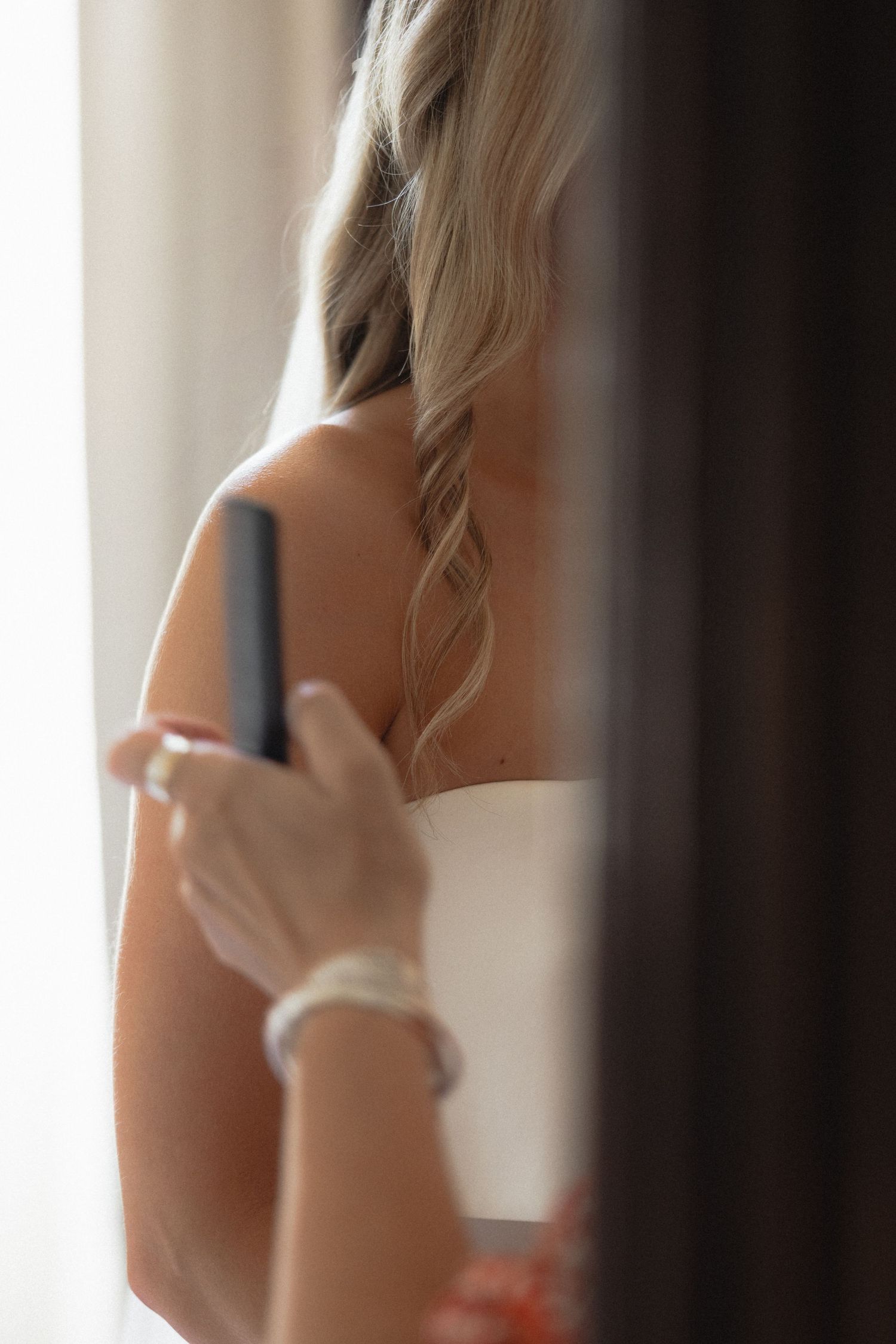 Side profile of a bride in a white strapless gown against a light background.