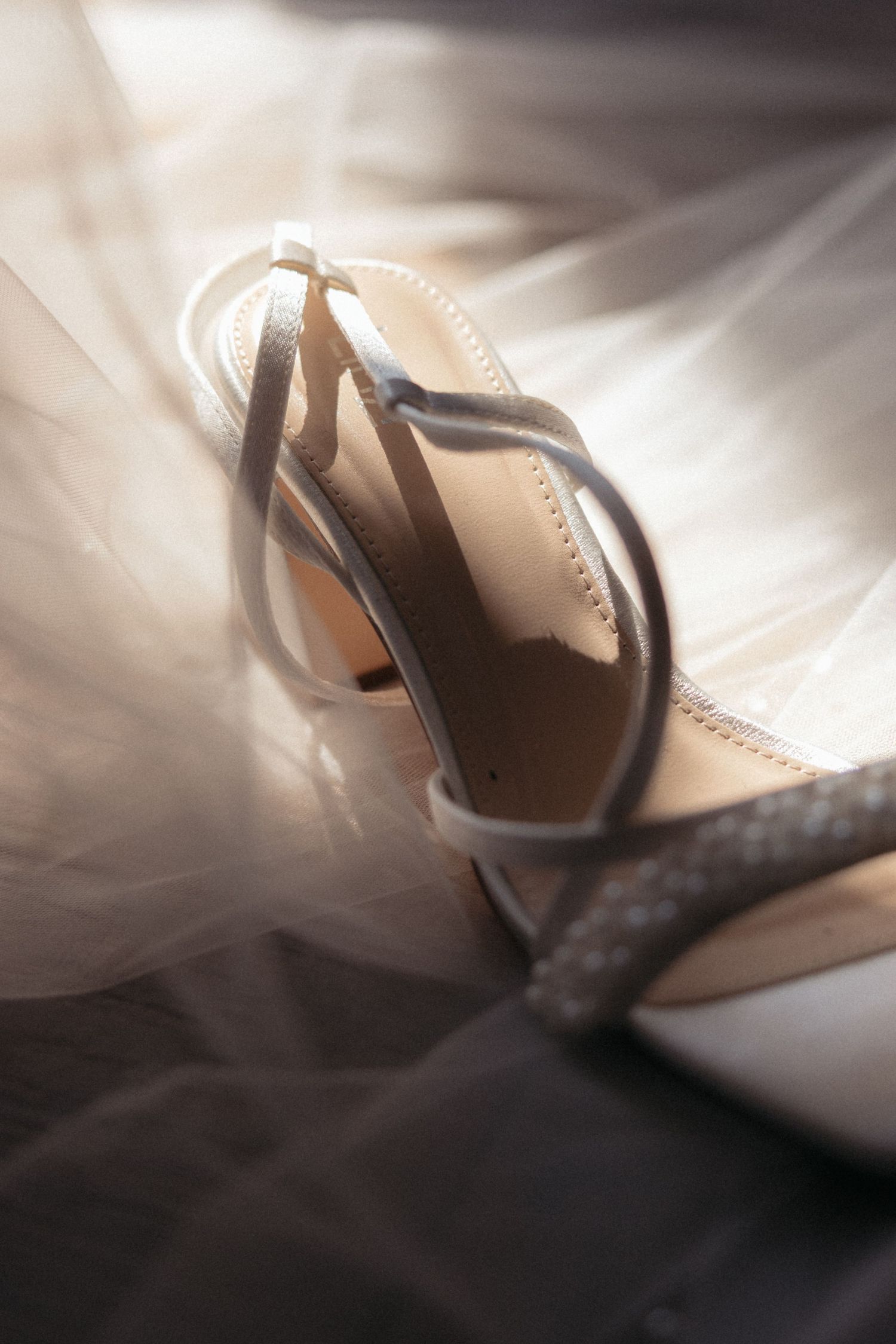 Artistic close-up of elegant bridal shoes with soft lighting and shadows.