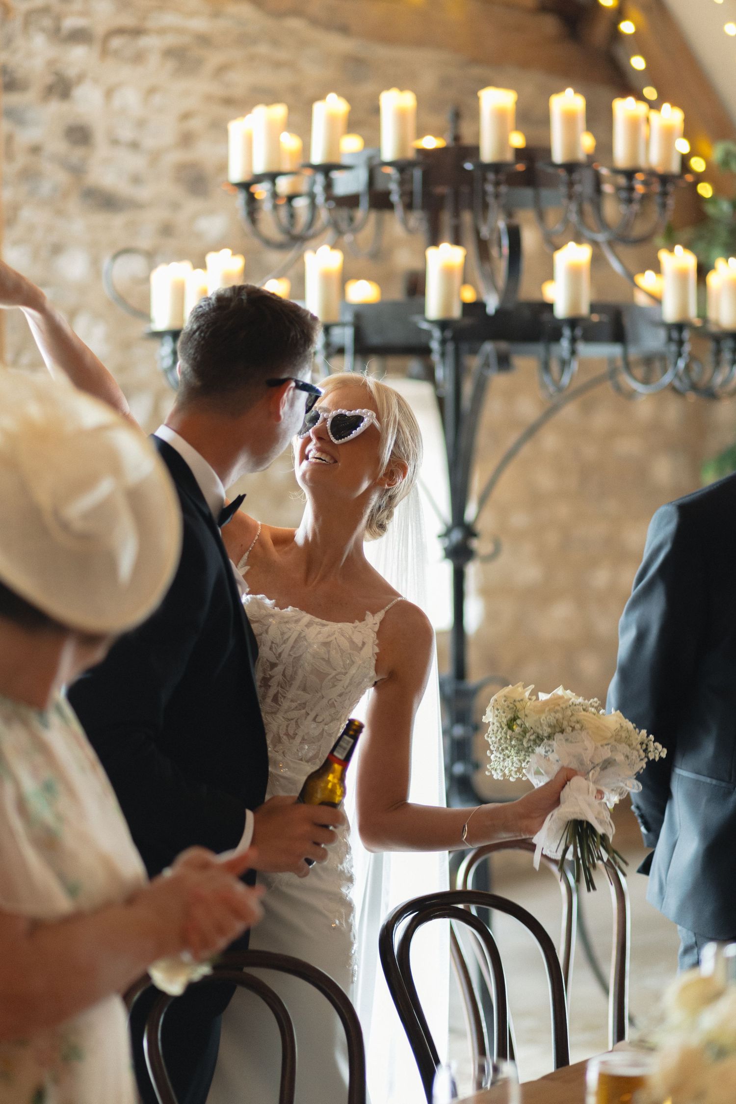 Wedding reception at a rustic venue with stone walls and candlelit chandeliers.