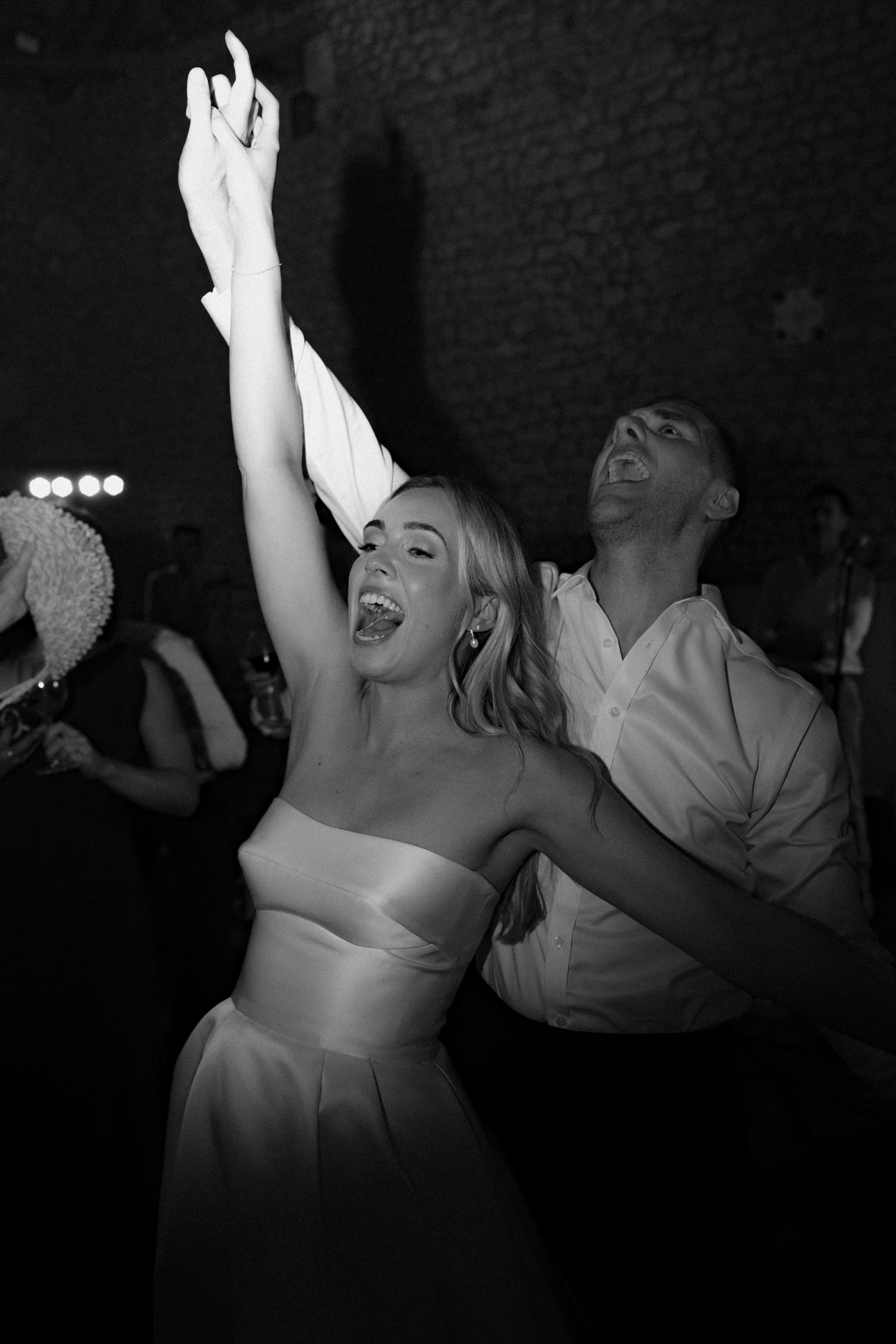 Black and white photo of wedding guests dancing enthusiastically at a reception.