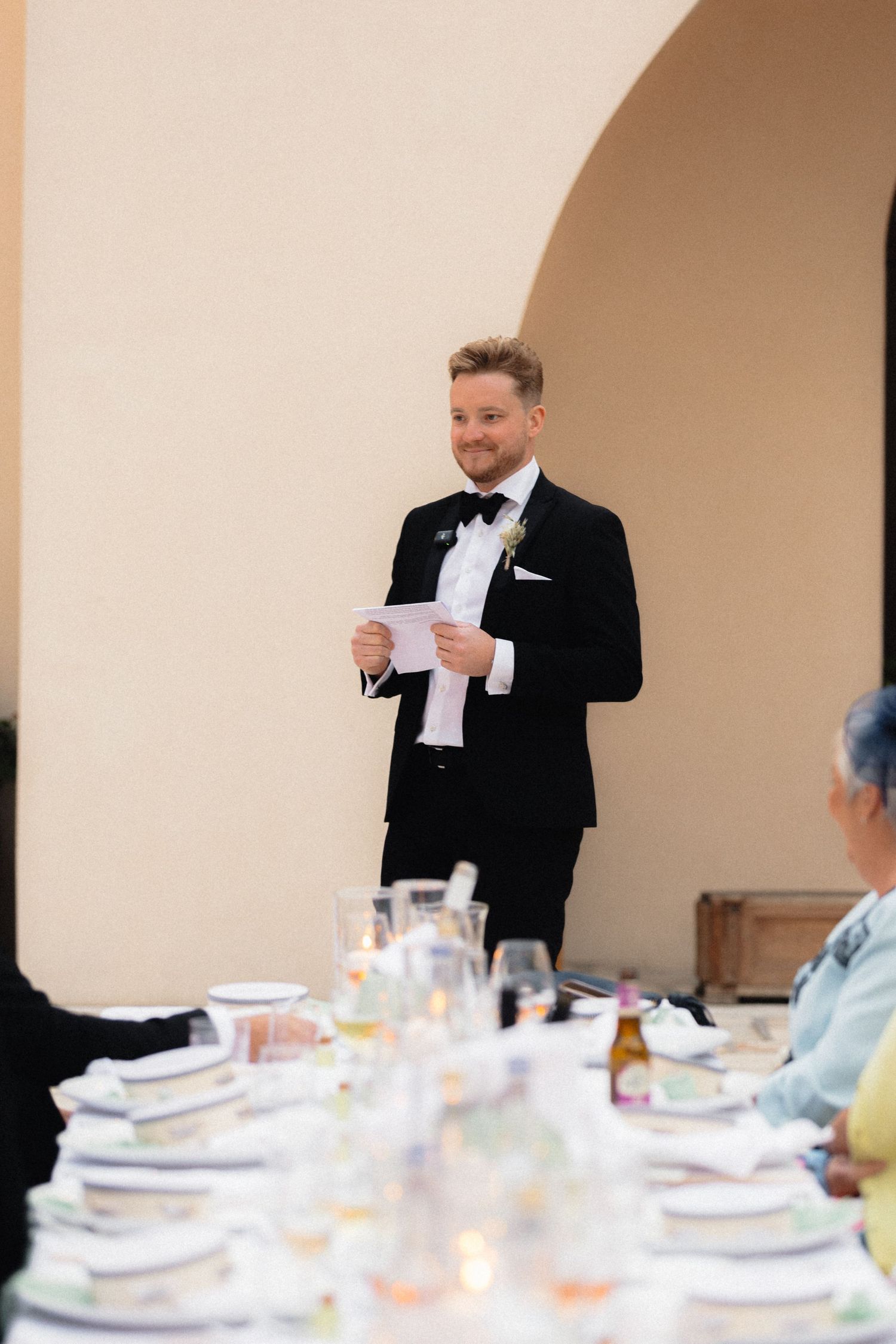 Guest giving a toast speech at an elegant indoor wedding reception.