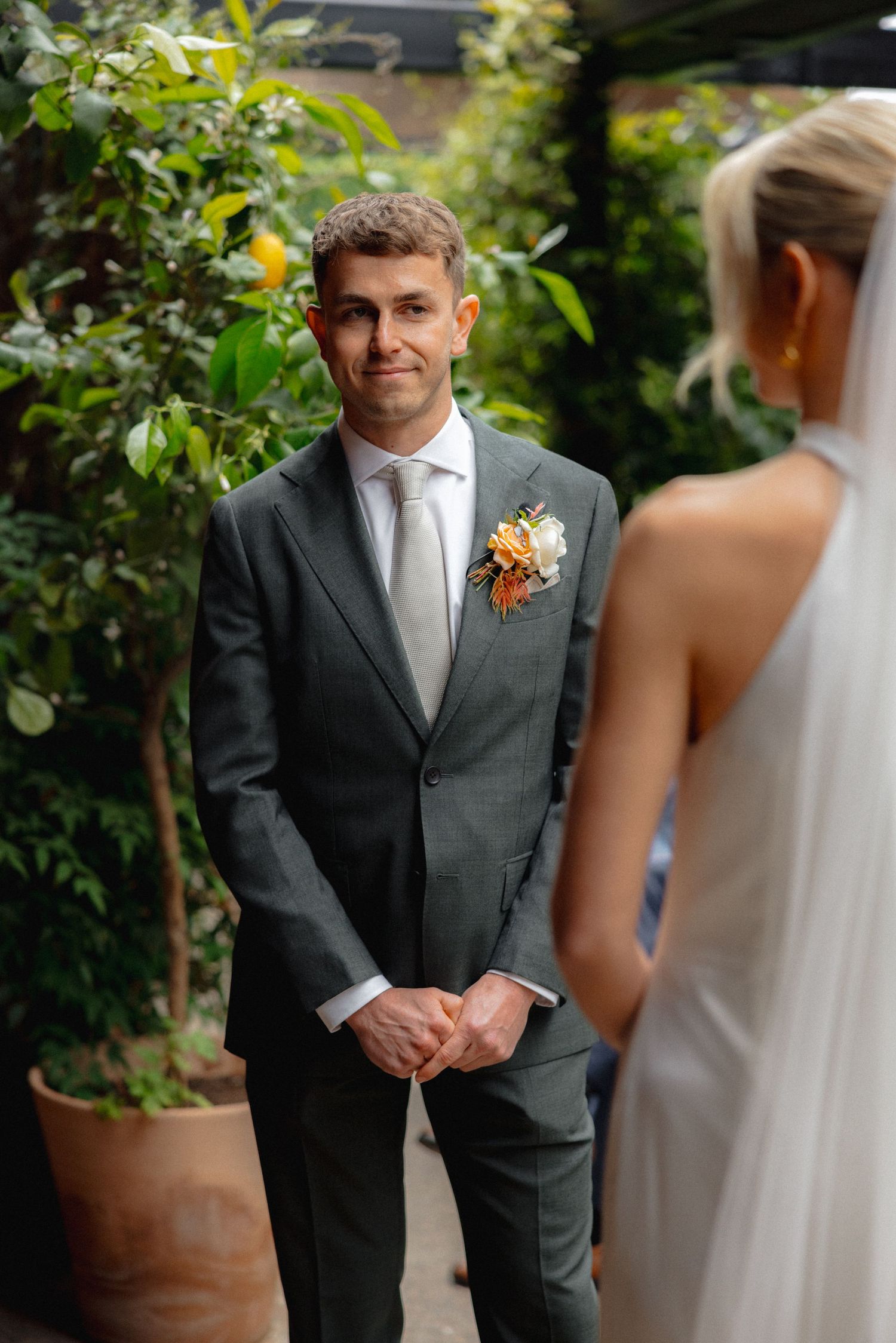 Wedding ceremony moment in lush garden setting with potted plants.