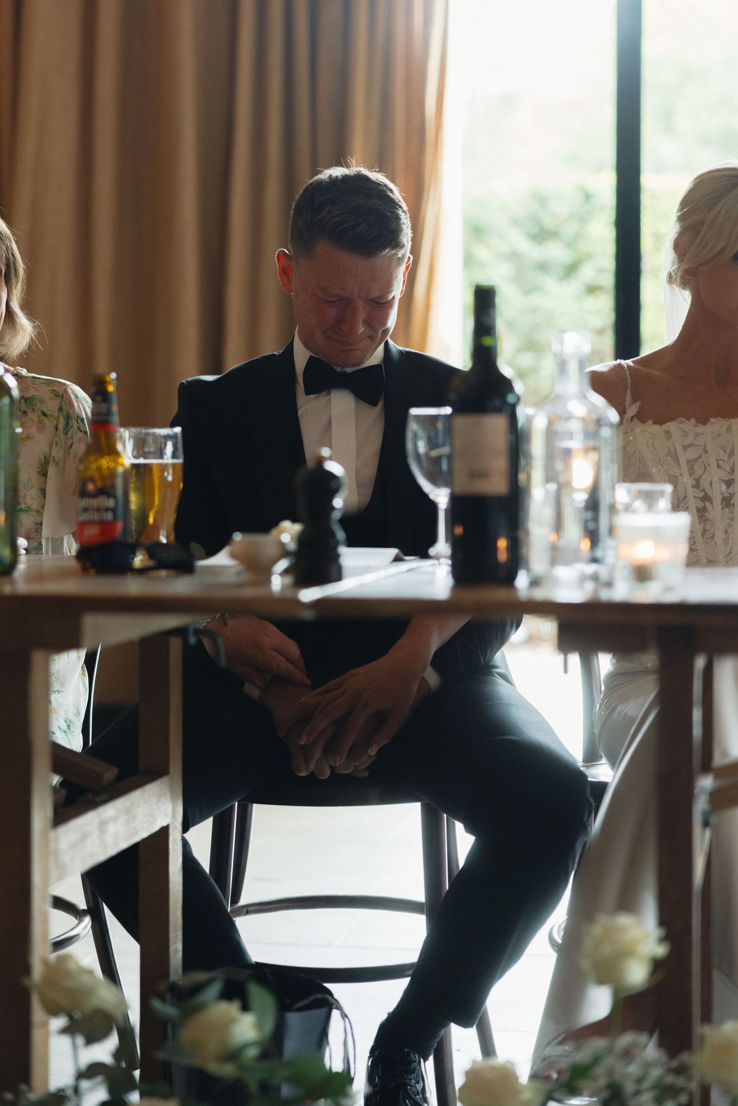 Wedding reception guests in formal attire seated at tables with ambient lighting.