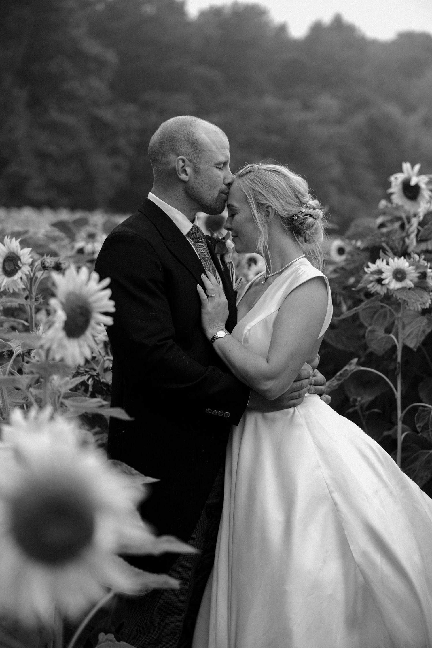 Black and white wedding photography sequence showing couple's romantic moment in sunflower field.
