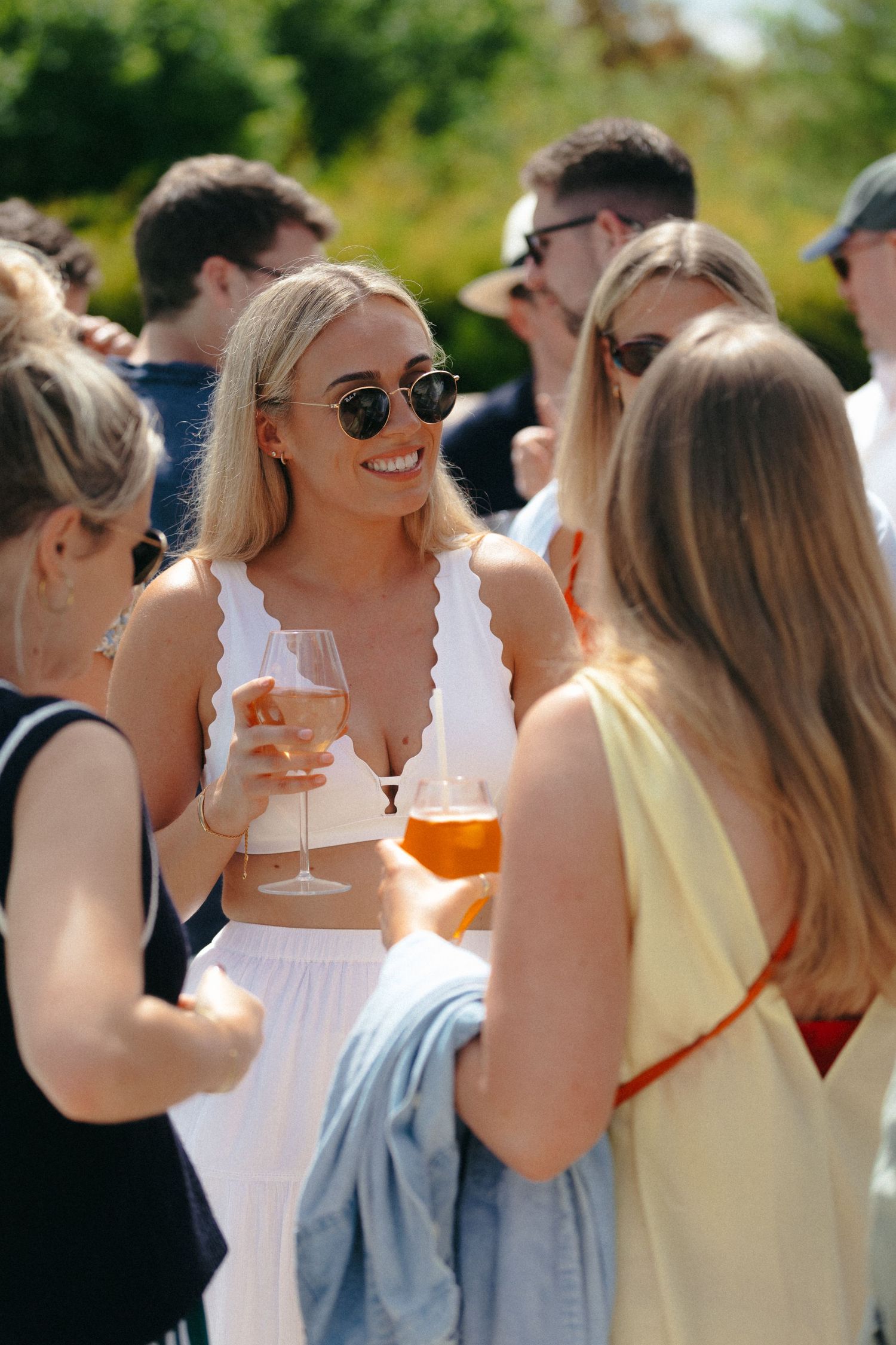 Friends enjoying drinks and conversation at an outdoor summer gathering.