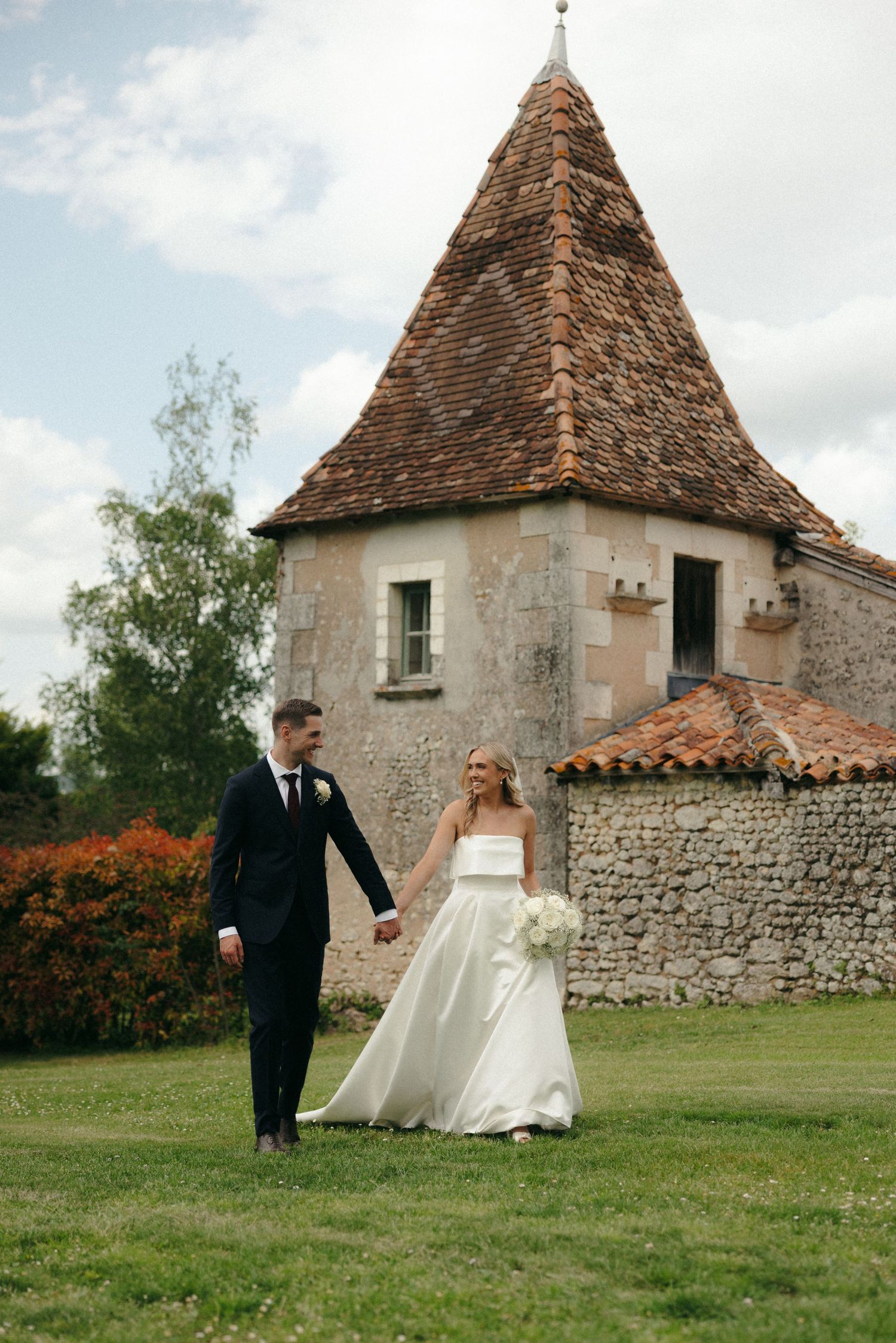 Stone castle building provides backdrop for wedding photos on green lawn.