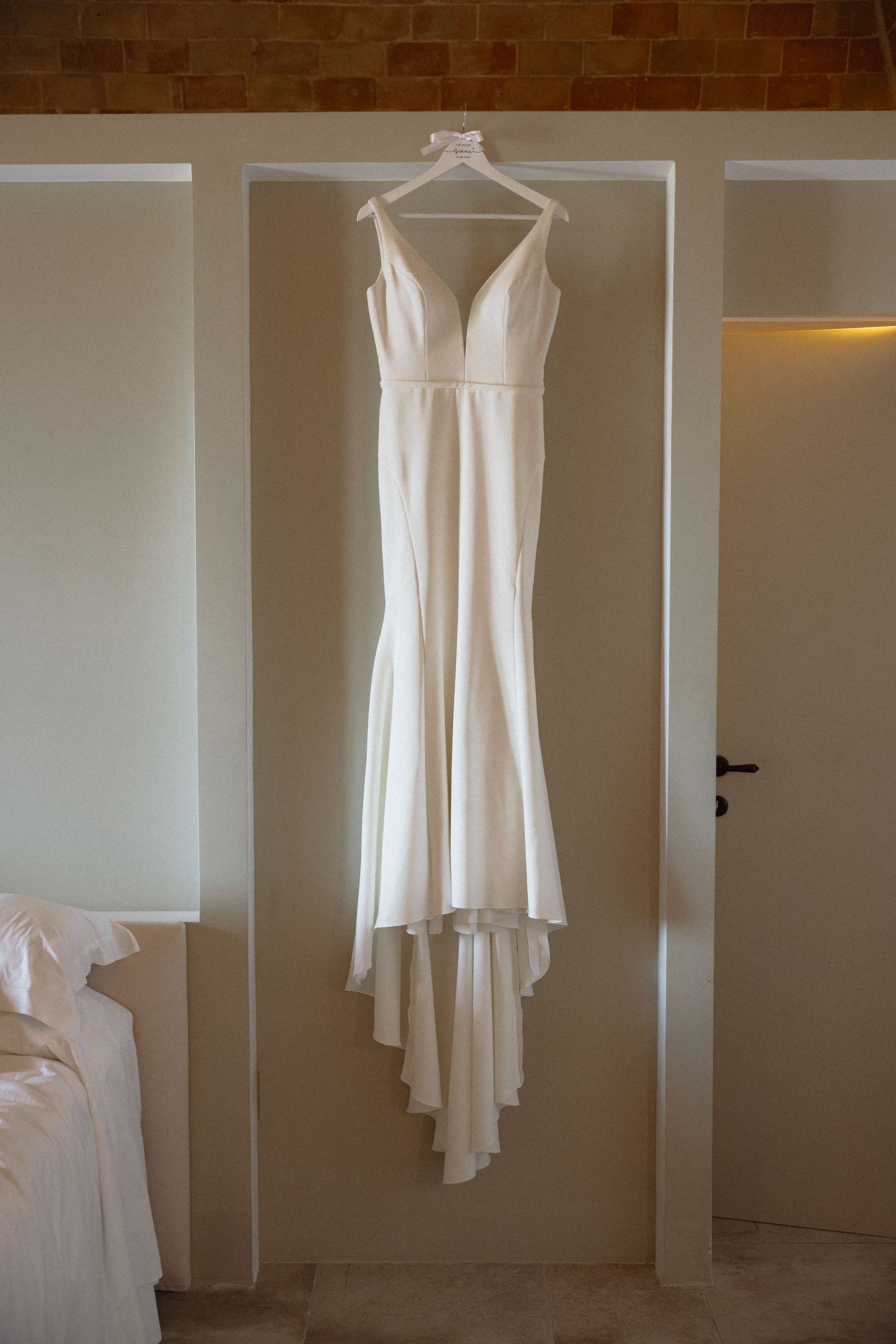 Elegant white wedding dress hanging on display against a neutral wall.