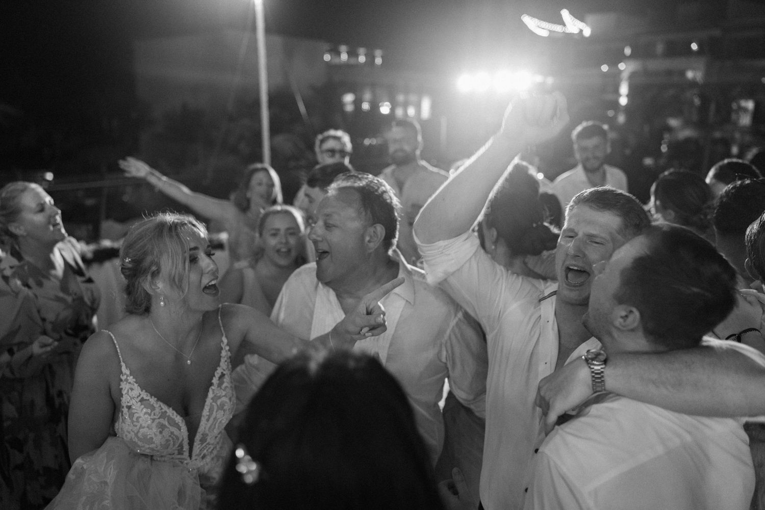 Joyful crowd dancing and celebrating at a wedding reception.