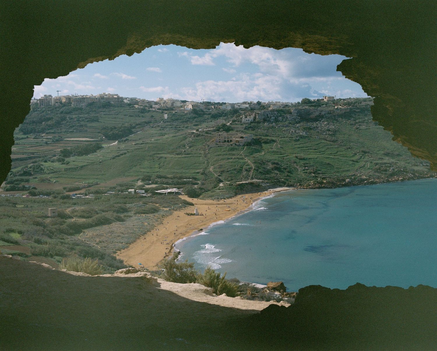 Panoramic coastal landscape with green hills and blue bay waters.