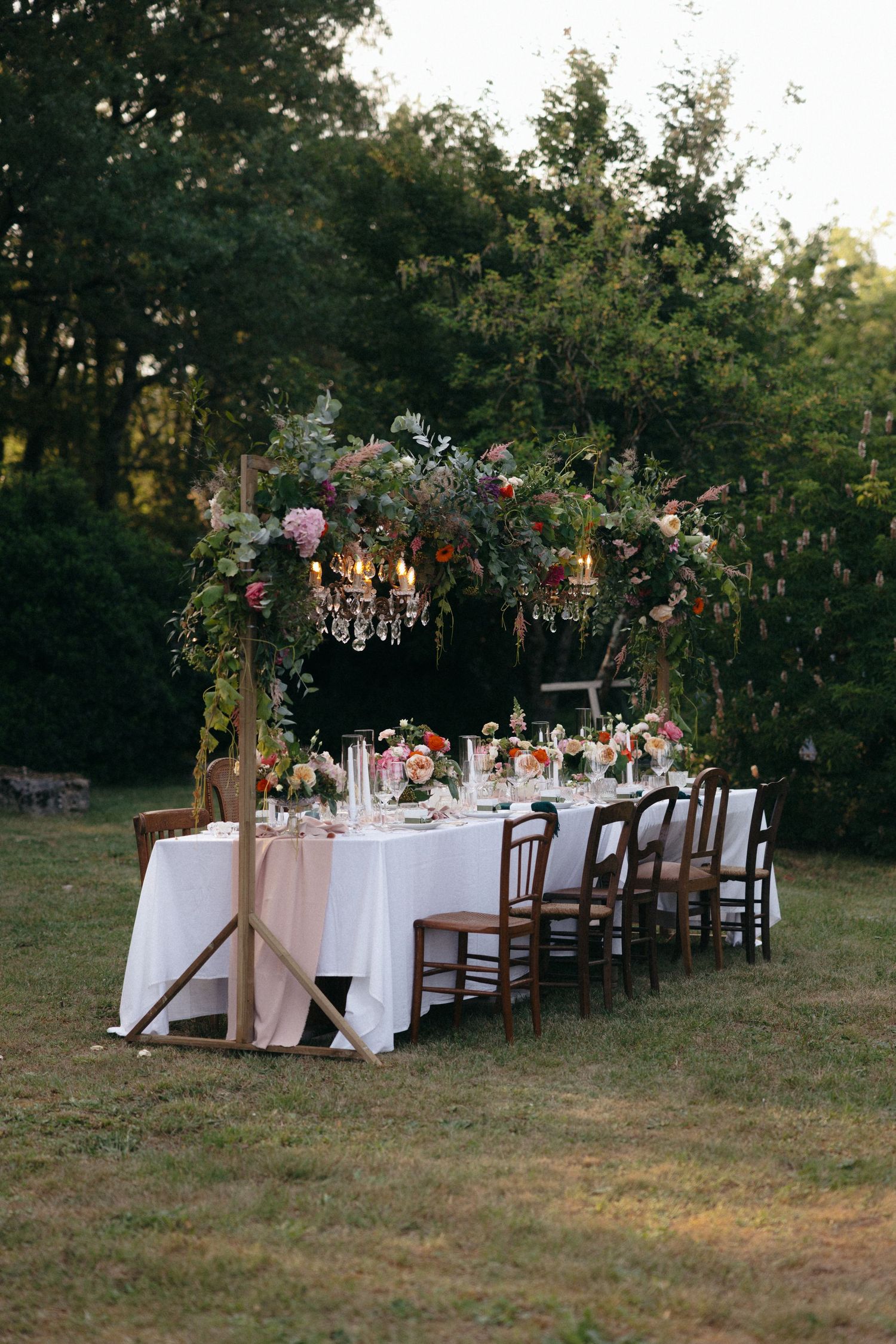 An elegant outdoor wedding reception table setup with white linens and floral centerpieces at sunset.