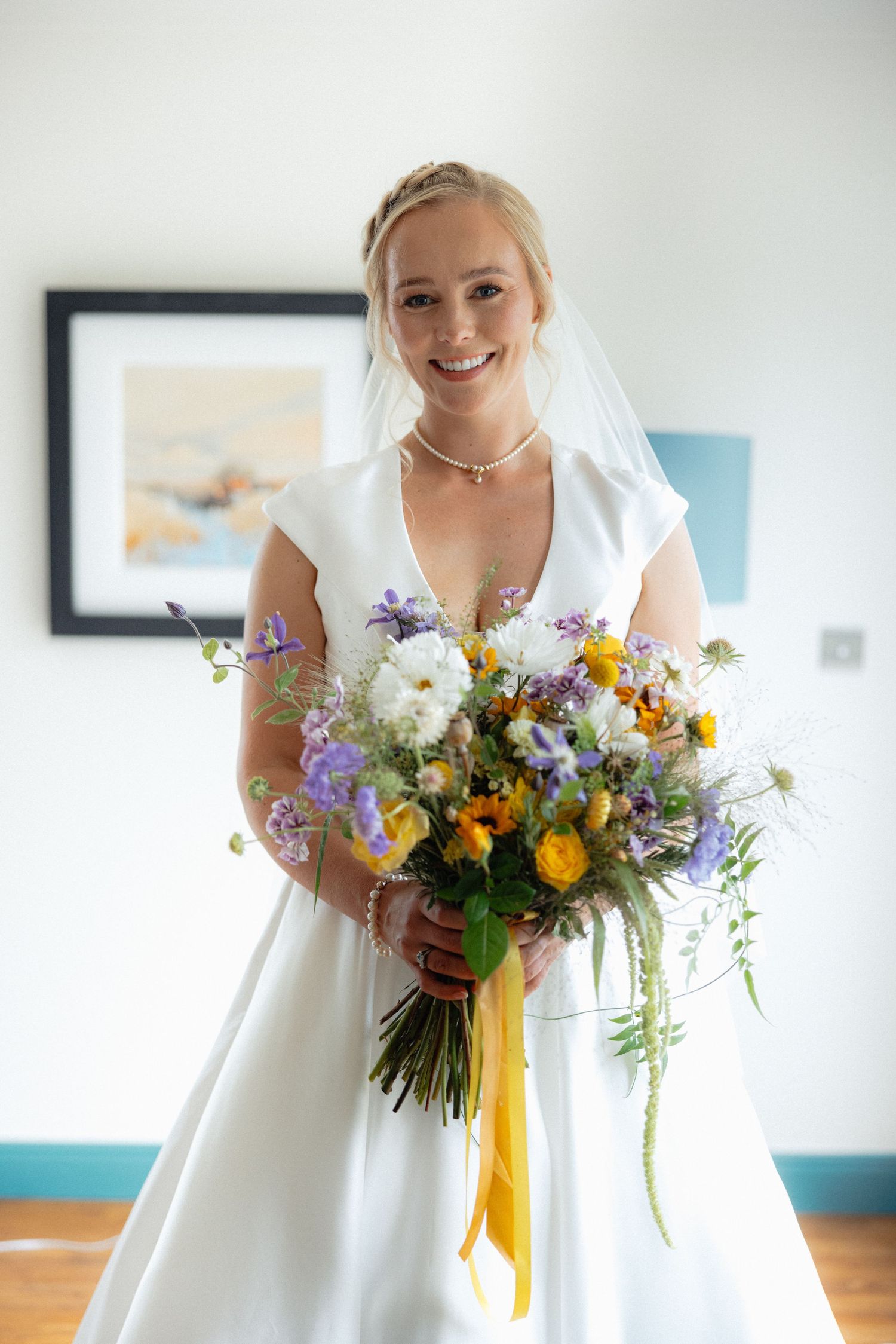 Bright wedding bouquet featuring purple and yellow flowers with flowing ribbons.