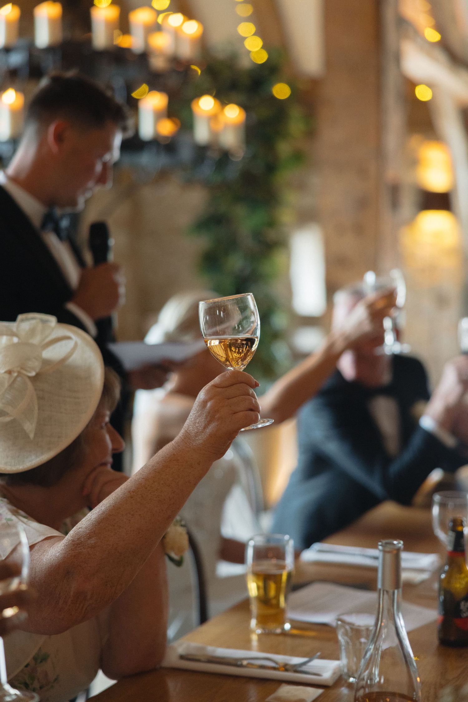 Wedding guests examine wine glasses during a tasting at an elegant reception with warm lighting.