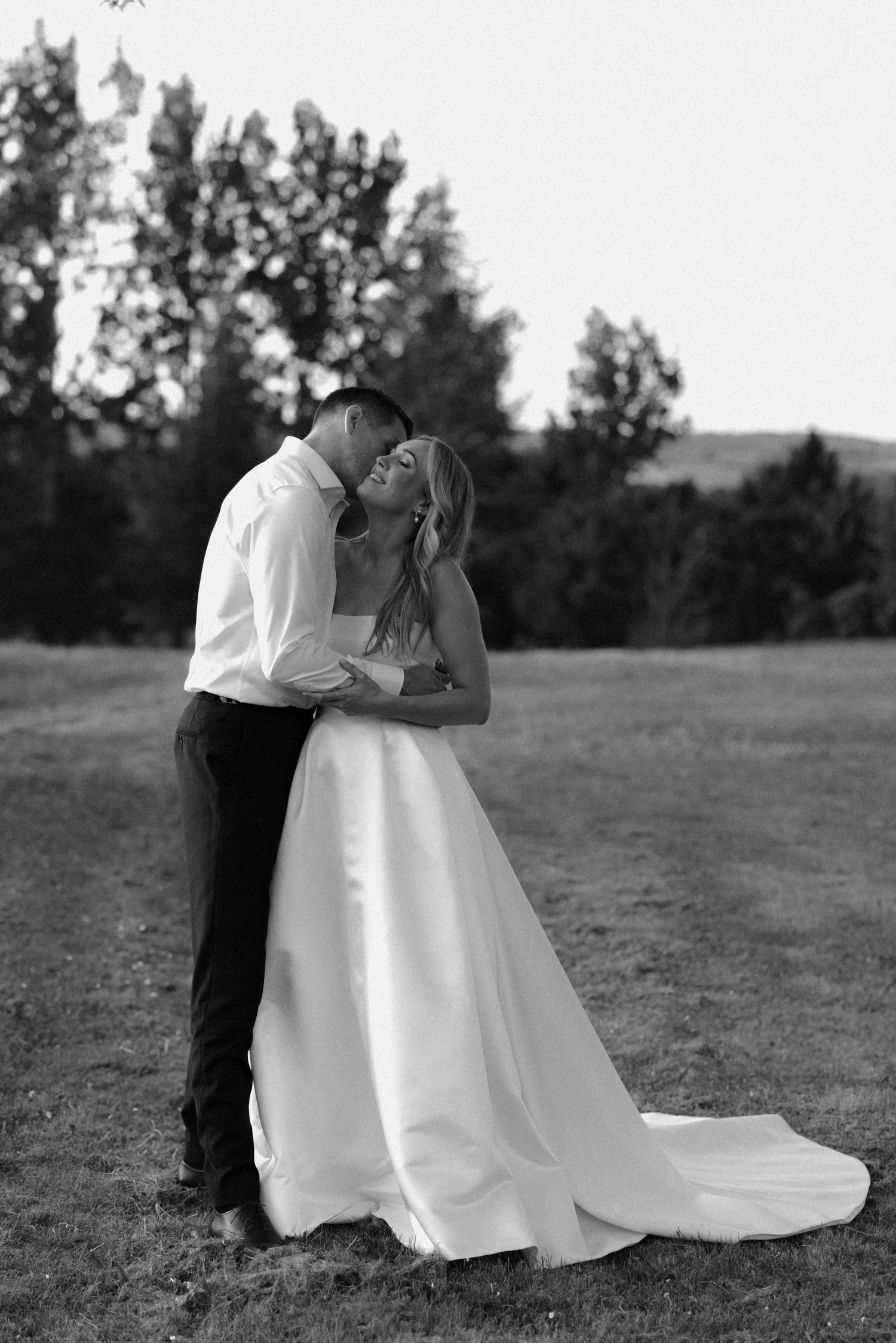 Romantic outdoor wedding portrait in a scenic field with flowing white dress.