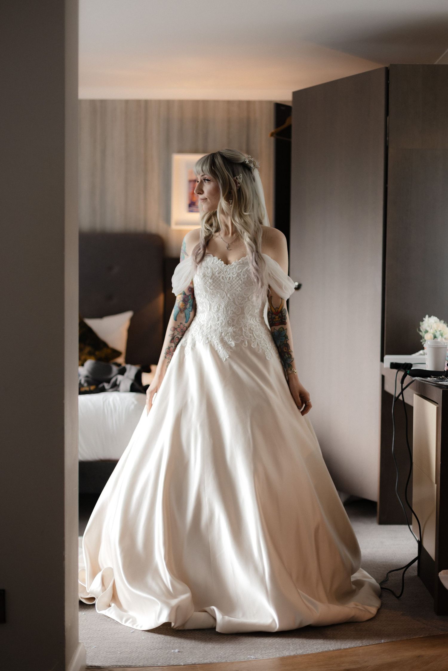 A stunning white wedding dress captured in a series of indoor preparation shots showing its elegant silhouette and details.