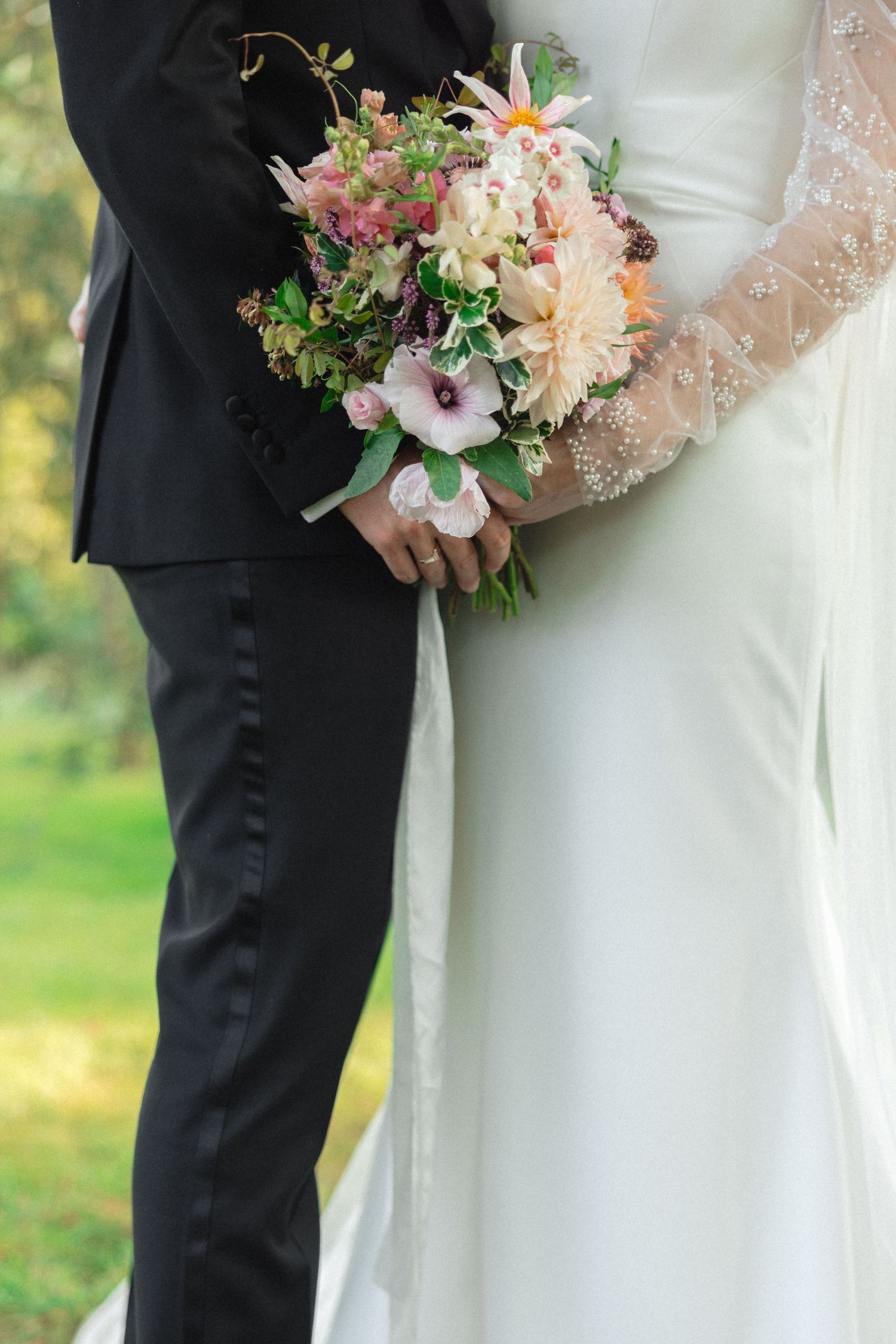 Close-up of wedding couple holding beautiful pink and white floral bouquet.