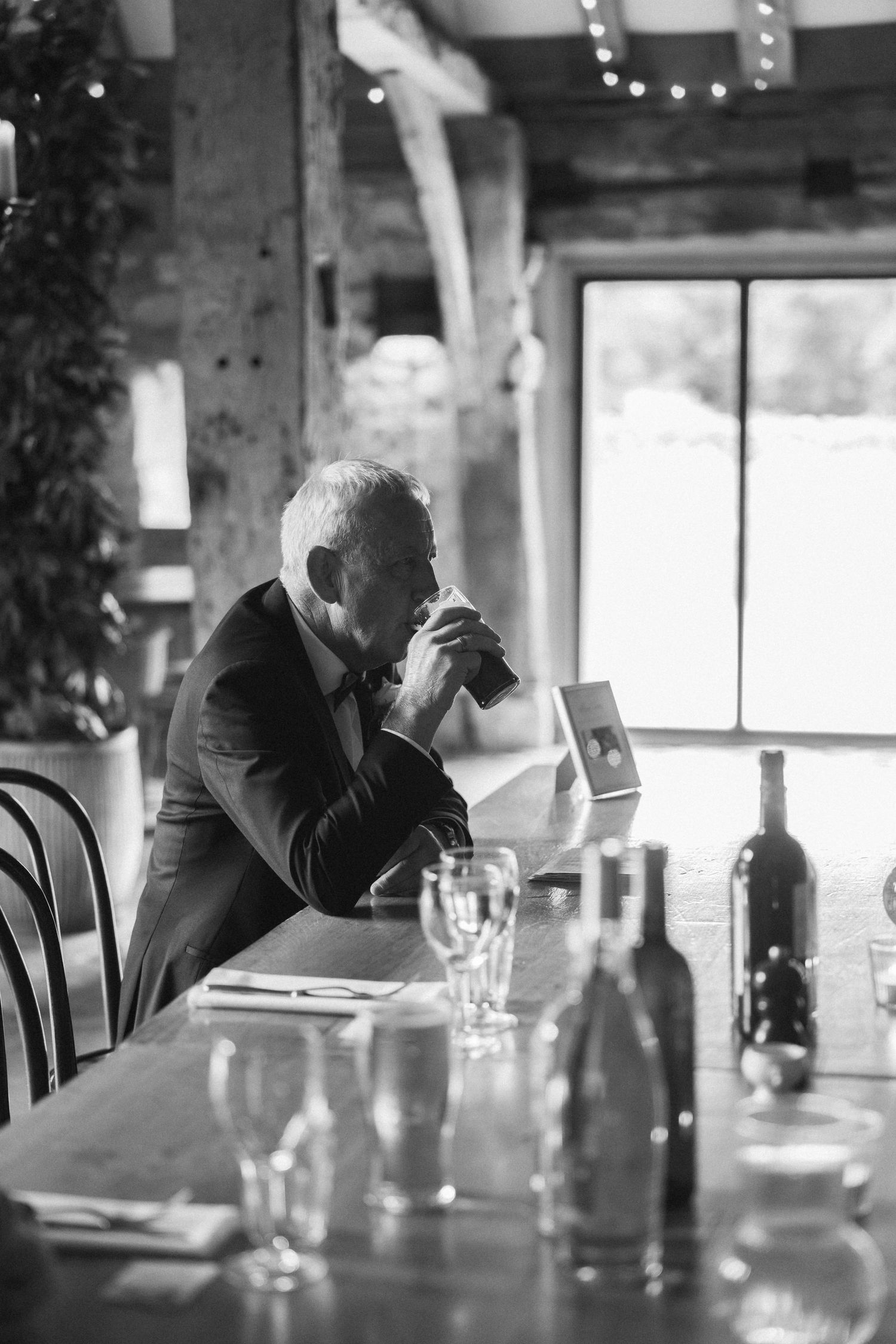A contemplative moment at an empty reception table with wine bottles and glasses.