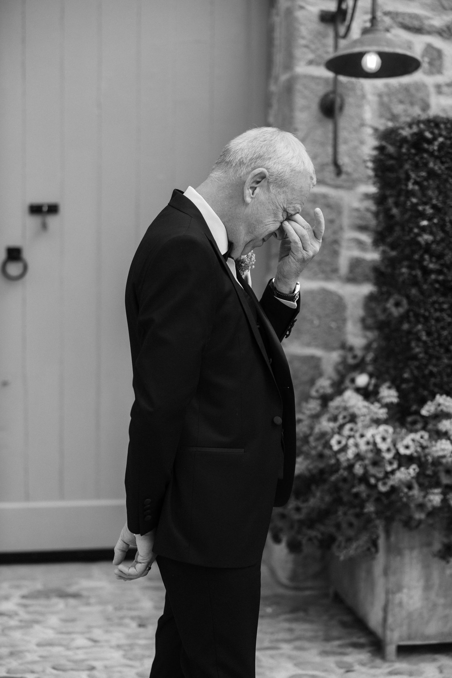 A gentleman in formal attire shows deep emotion during a wedding moment.