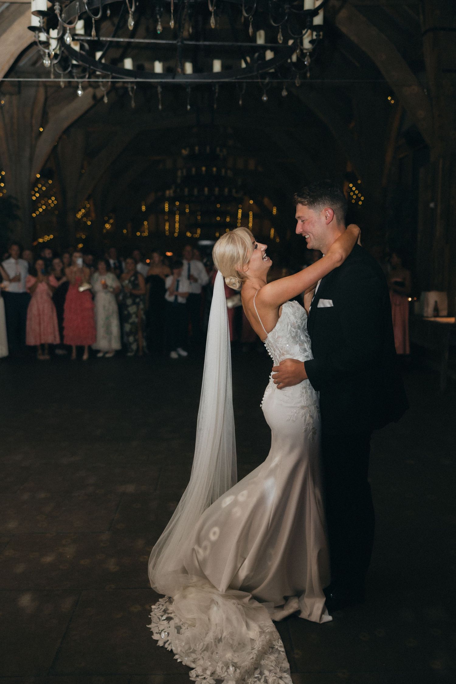 A romantic first dance between newlyweds under dramatic lighting in a rustic venue.