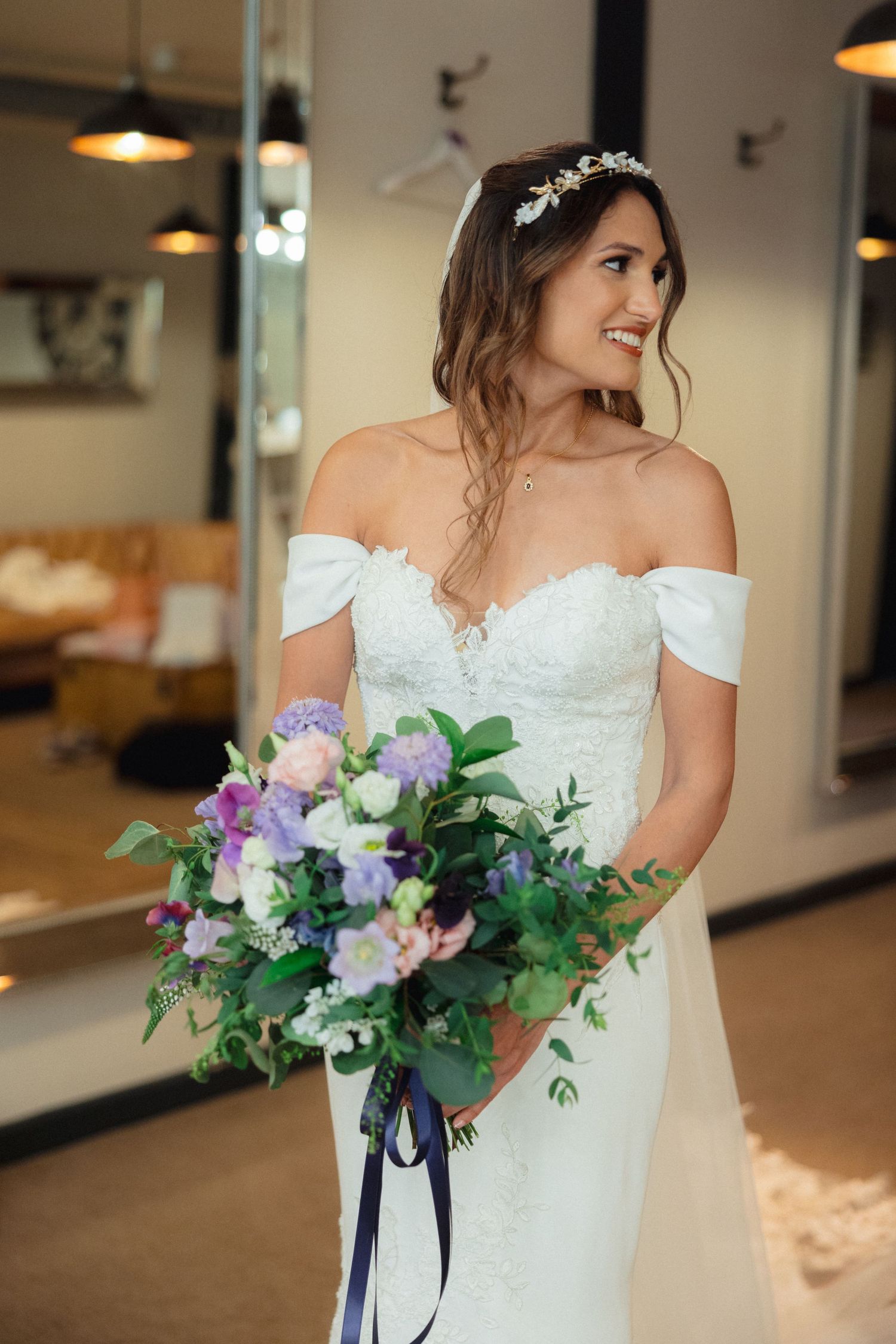 A bride holds a beautiful purple and white floral bouquet with trailing ribbons.