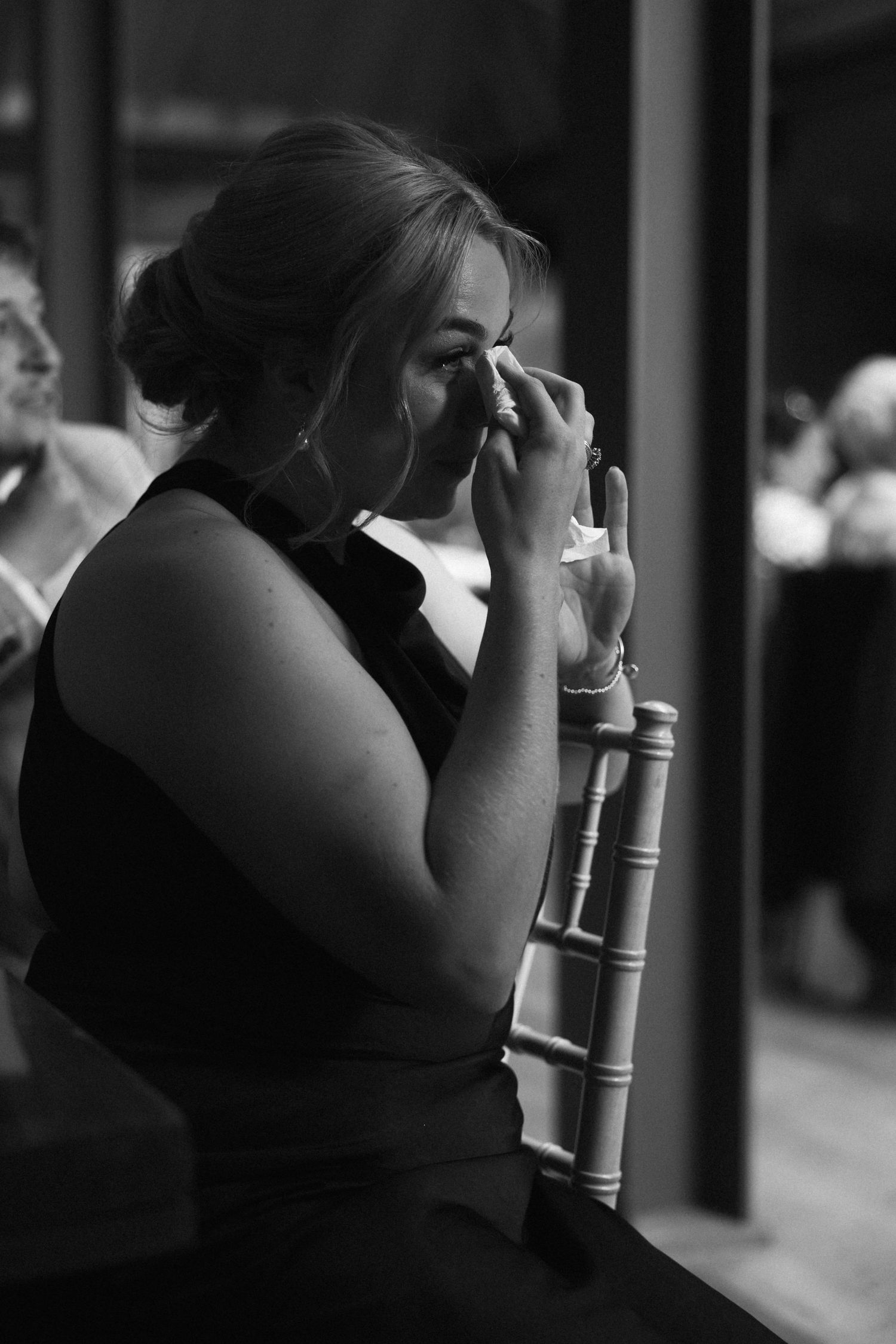 A black and white candid photo of guests seated at a wedding reception.