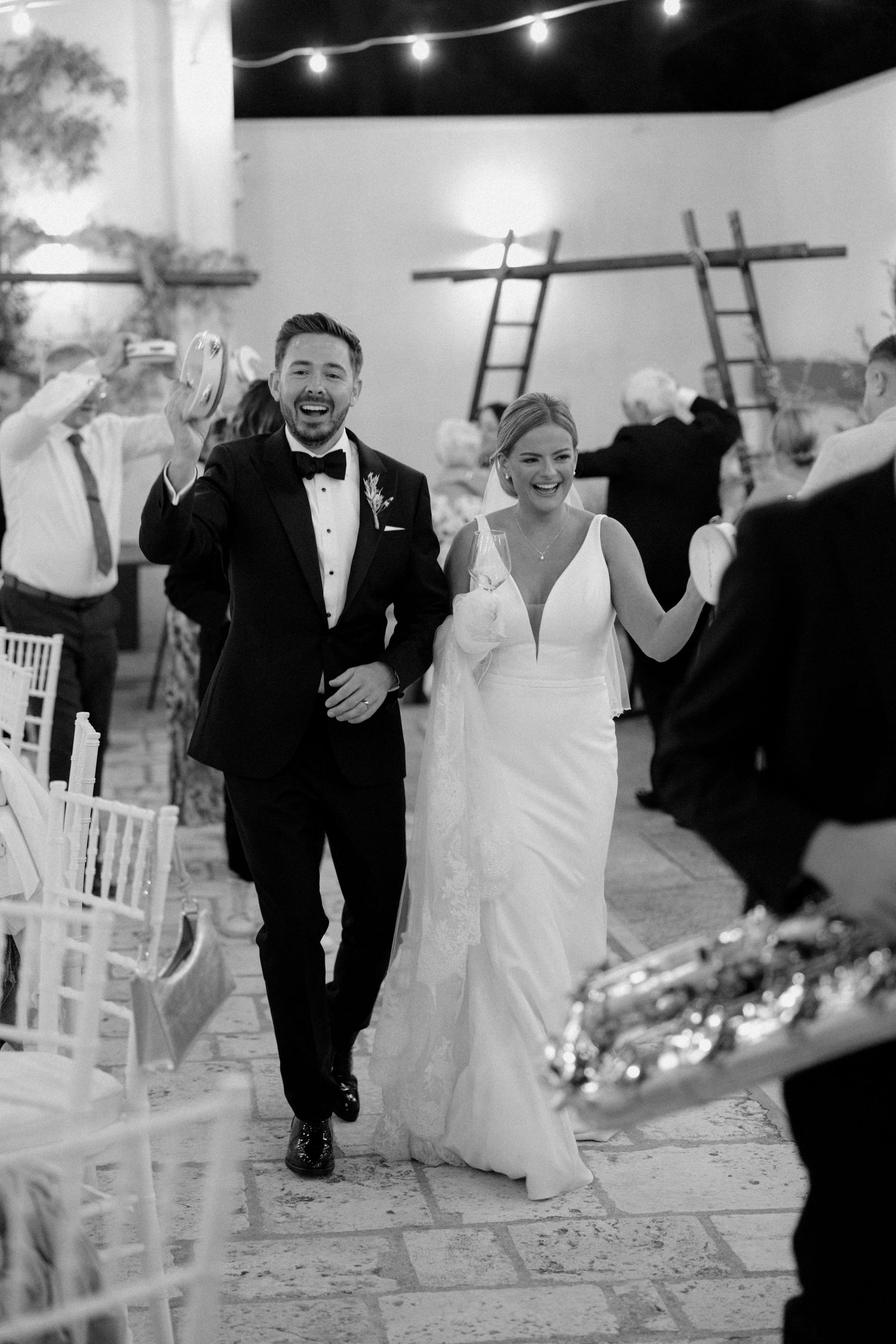 Wedding party running and laughing down a path under string lights.