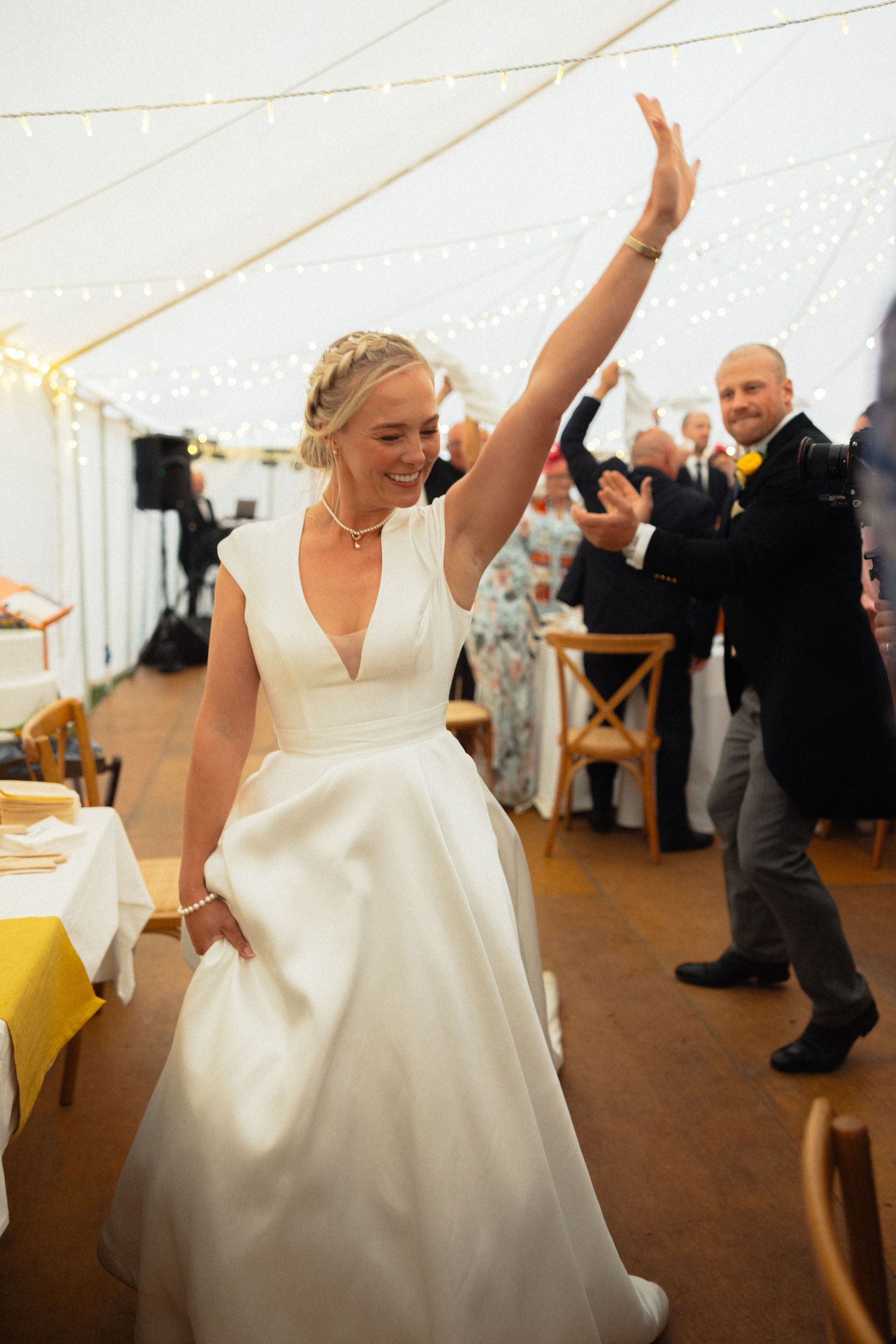 Joyful dancing moments captured during a wedding reception in a white tent venue.