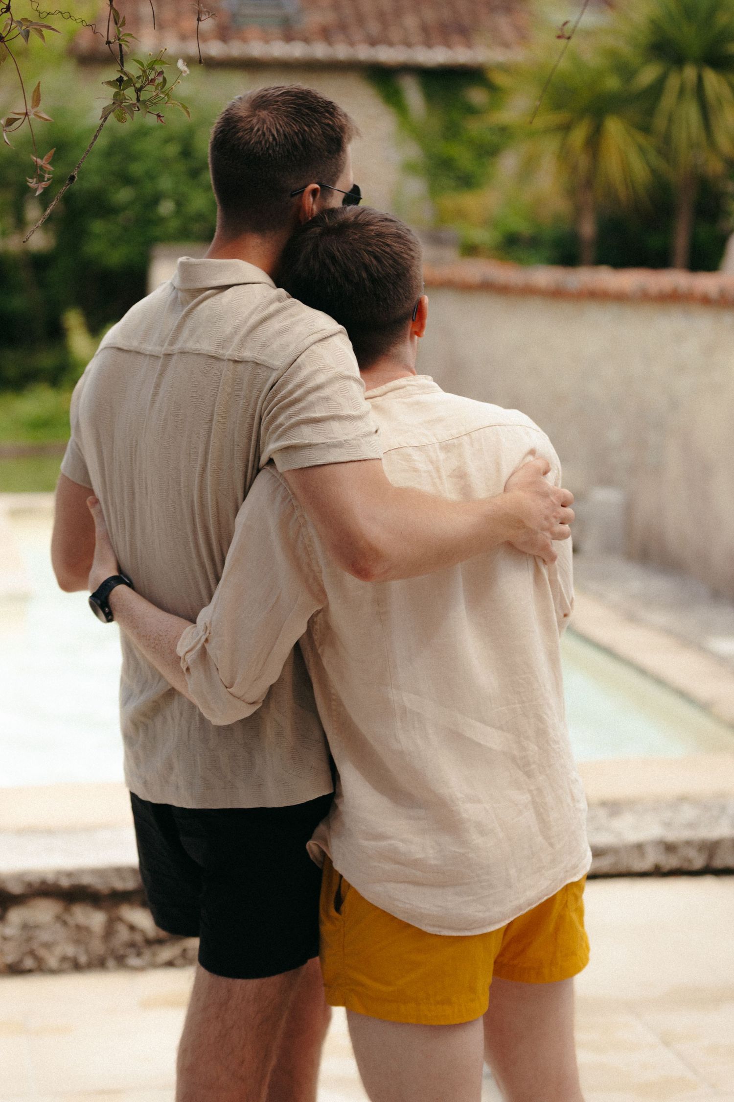 Friends walking together with arms around each other on a sunny path.