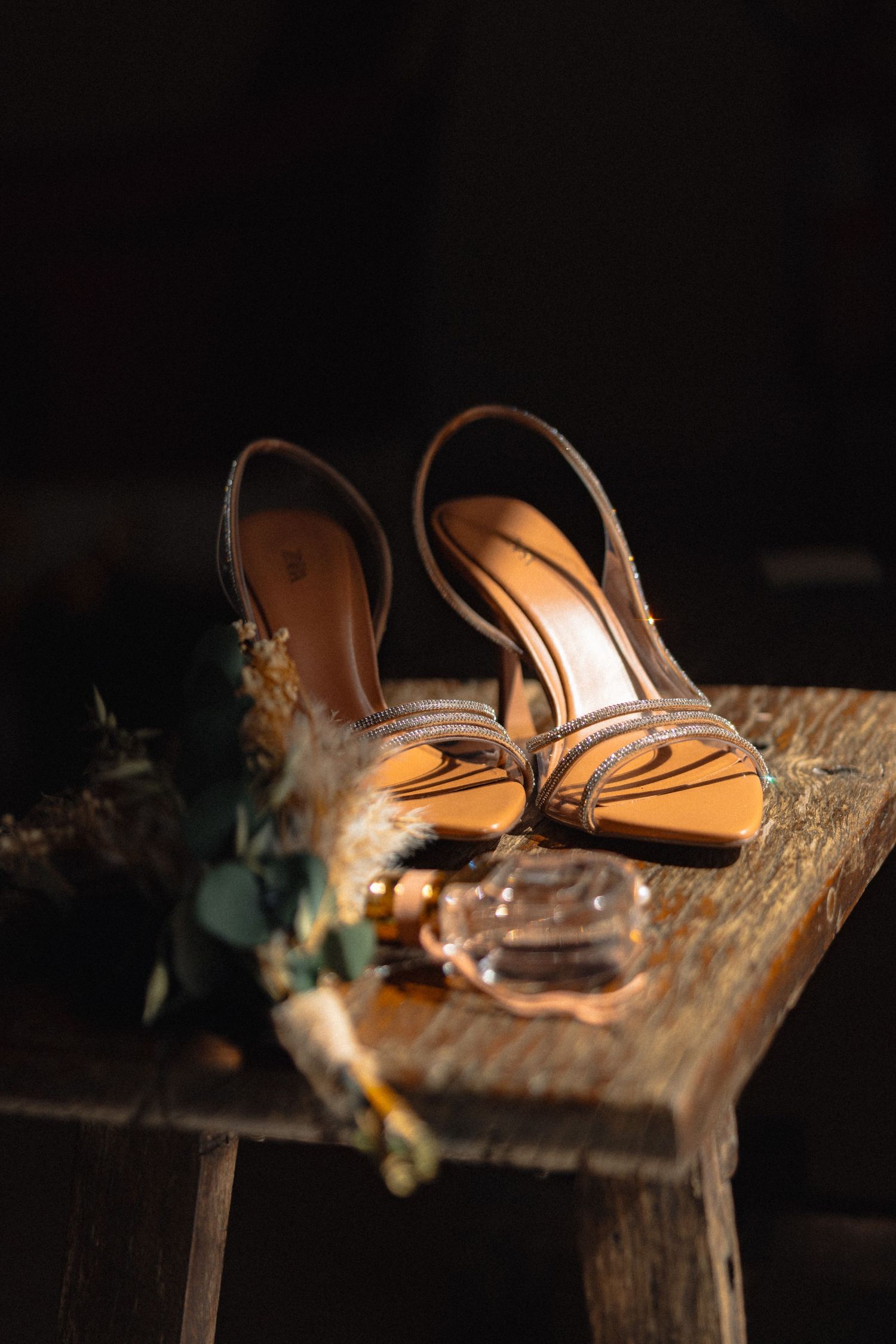 Elegant brown wedding shoes photographed on rustic wooden surface with decorative elements.