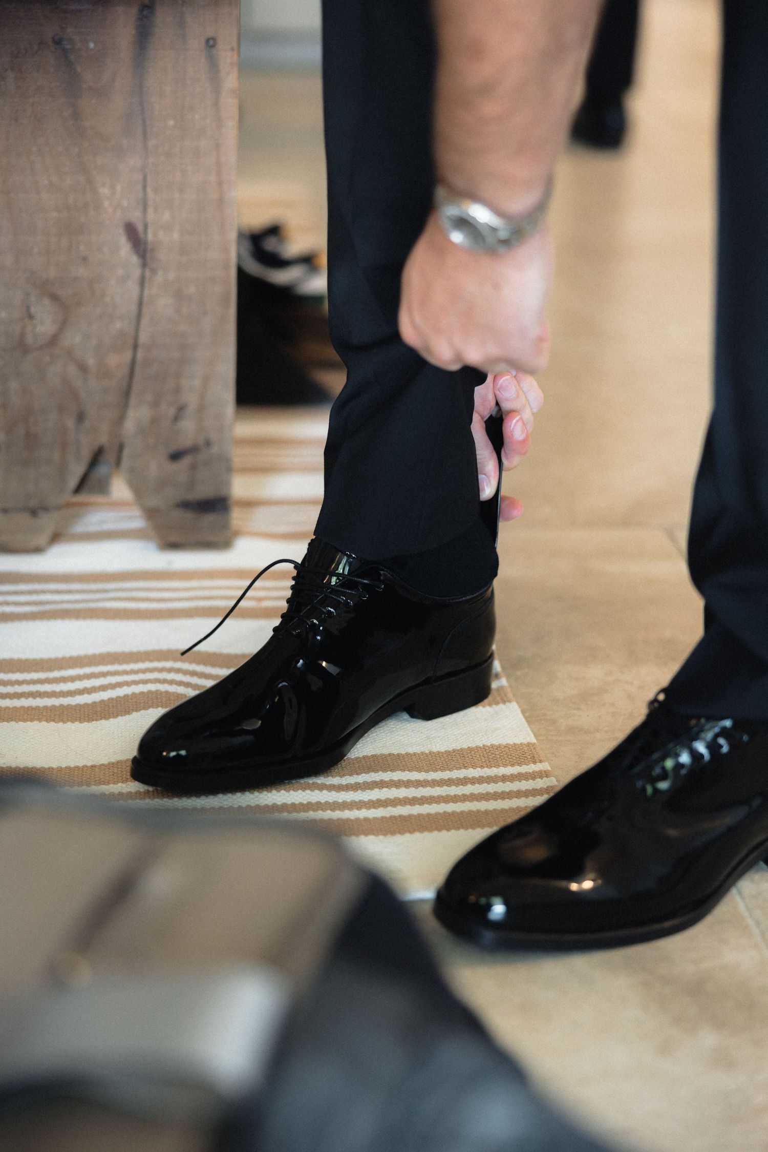 Close-up of formal black dress shoes on patterned floor at special event.