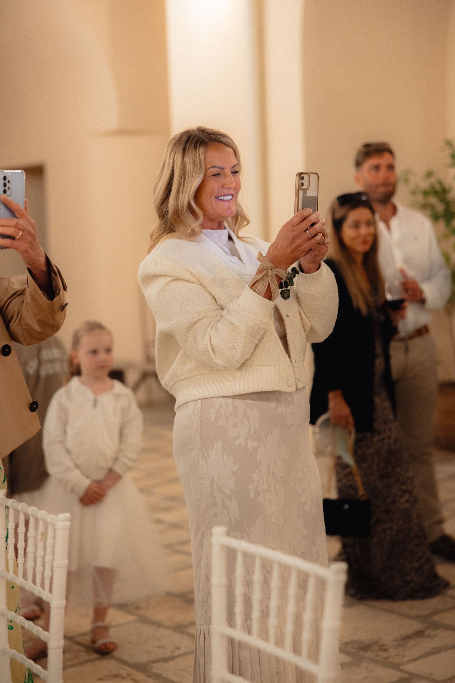Wedding guest in white outfit reacting excitedly at reception.