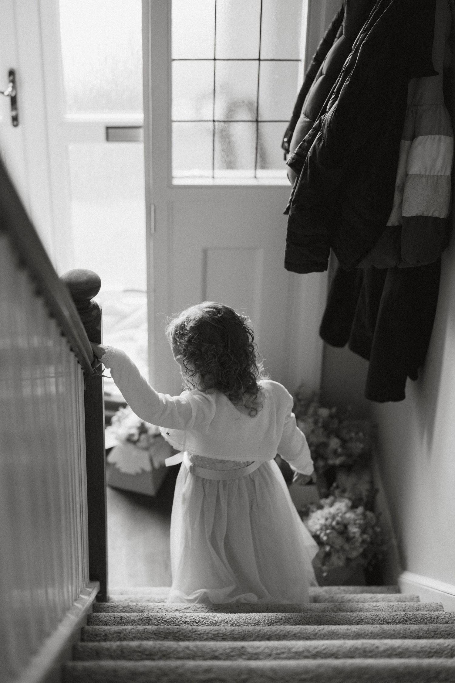 Black and white image of flower girls sitting on stairs in flowing white dresses.