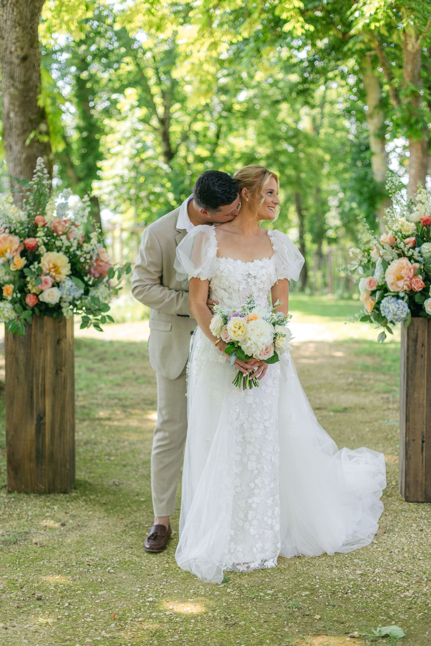 Wedding photography session showing details of a white lace dress and floral bouquet in a forest setting.