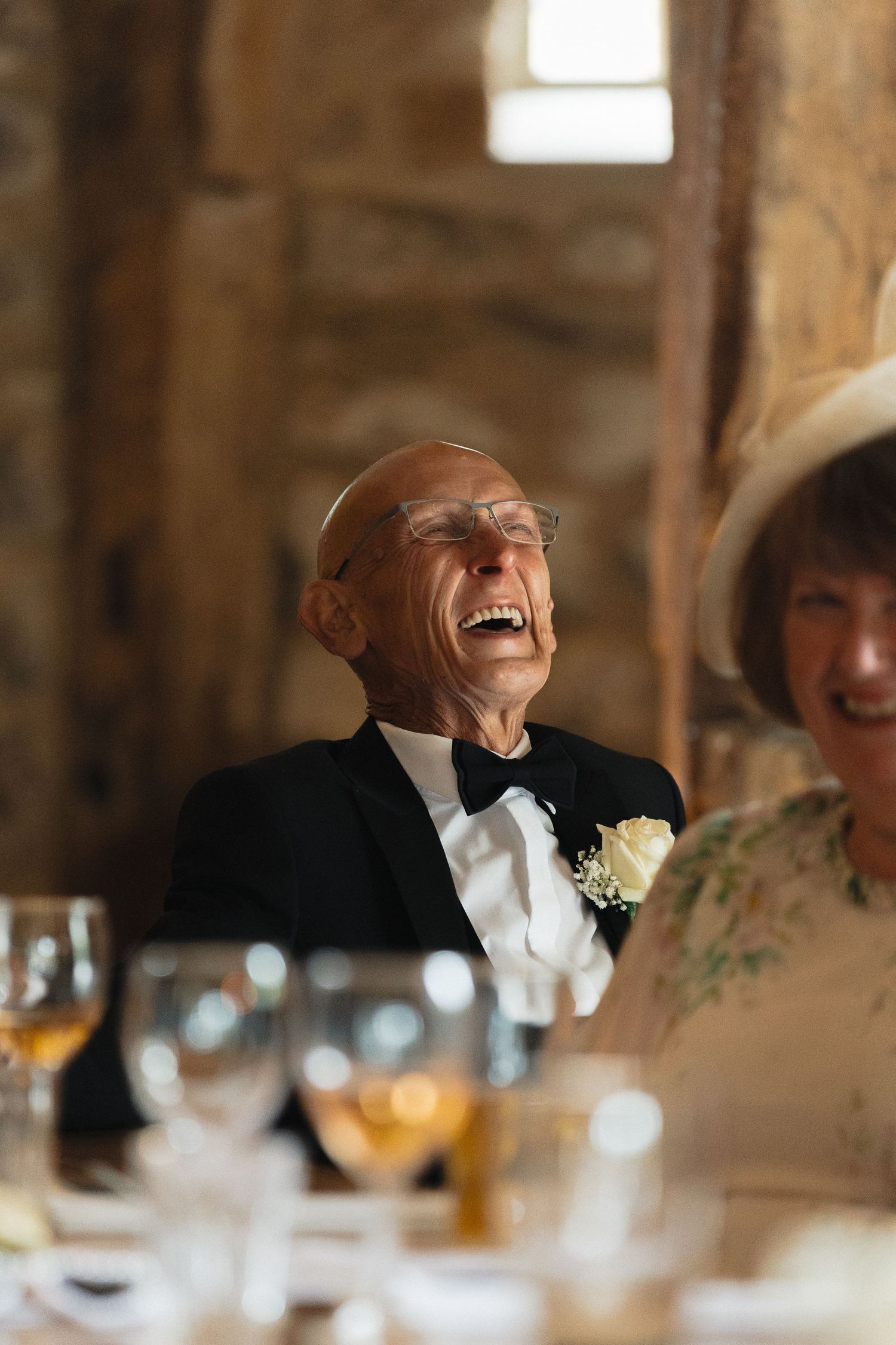 Joyful reactions during speeches at an elegant reception with stone walls and table settings.
