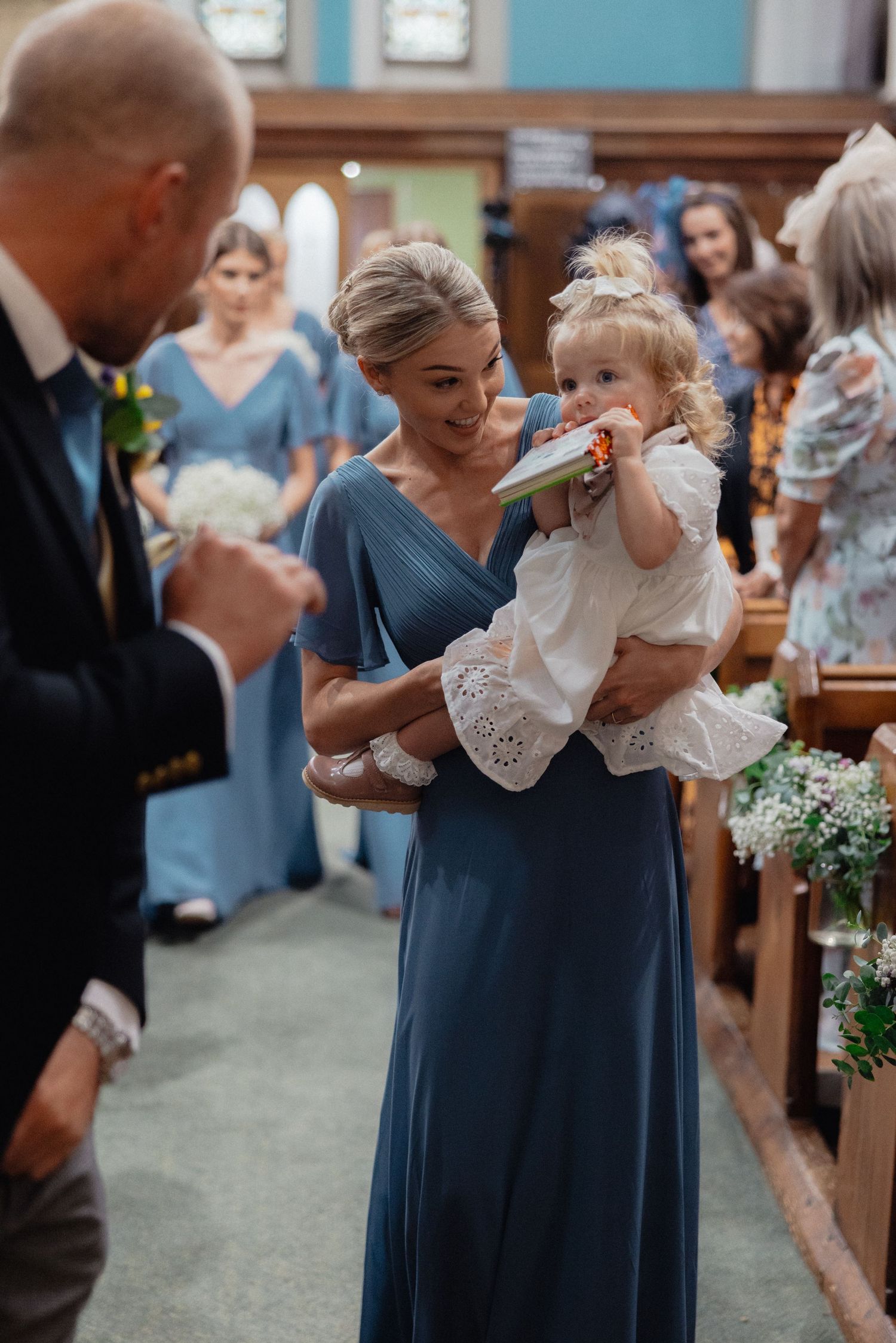 Wedding ceremony in a church with attendants in blue dresses holding bouquets.
