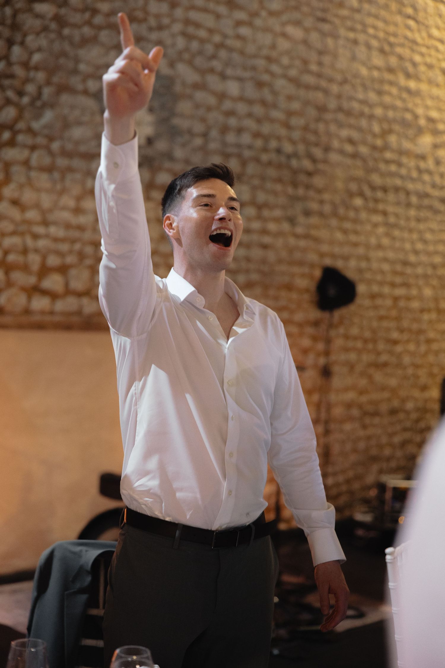 Performer in white shirt and black tie sings passionately during wedding entertainment.
