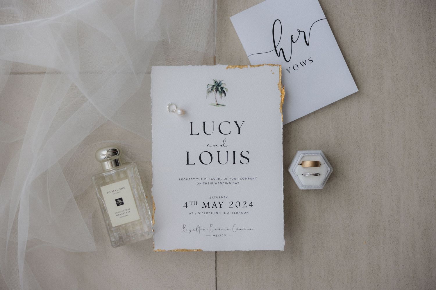 Elegant wedding invitation suite with white paper and delicate details laid on a neutral surface.