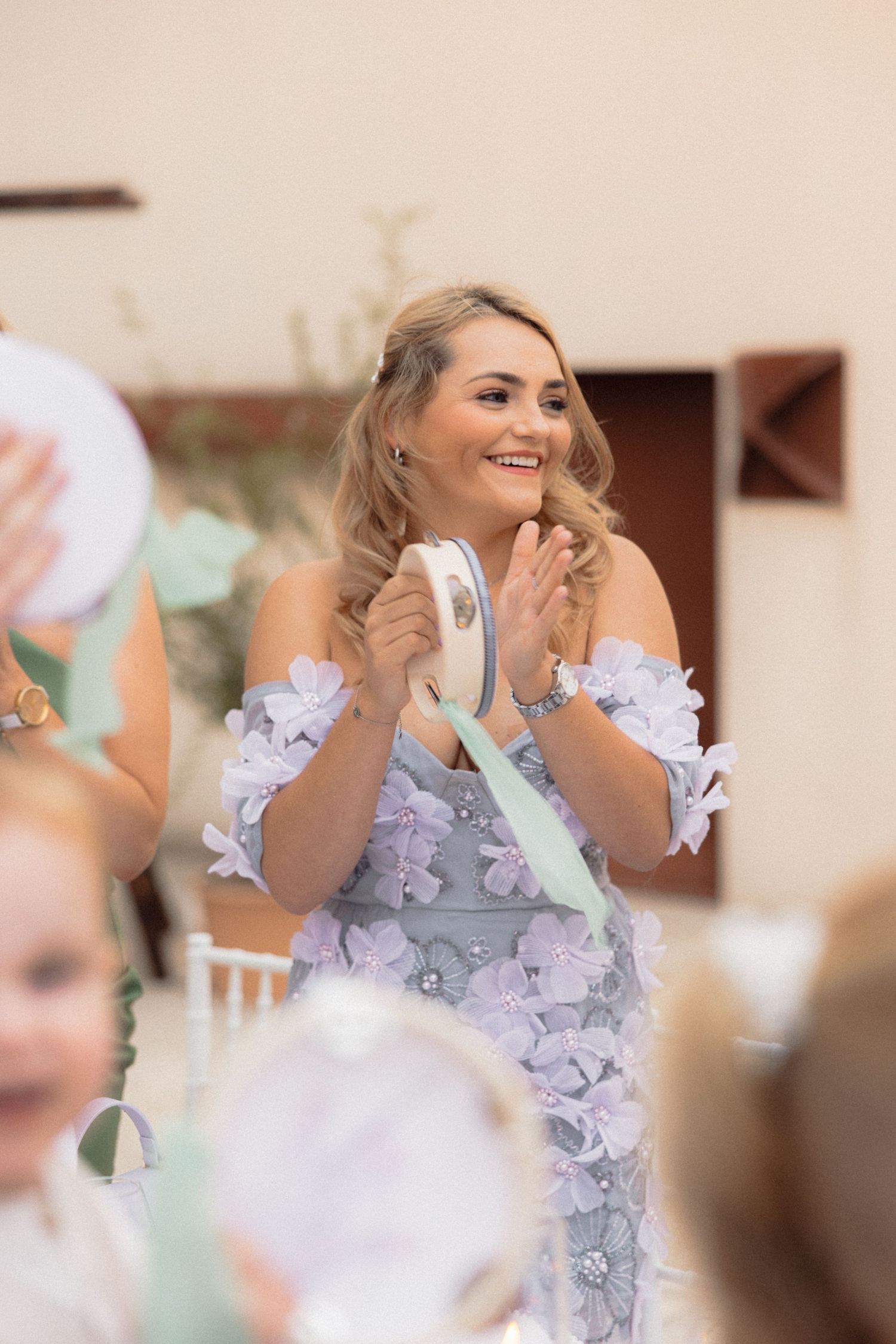 Wedding guest in lavender dress laughs joyfully during reception celebration.