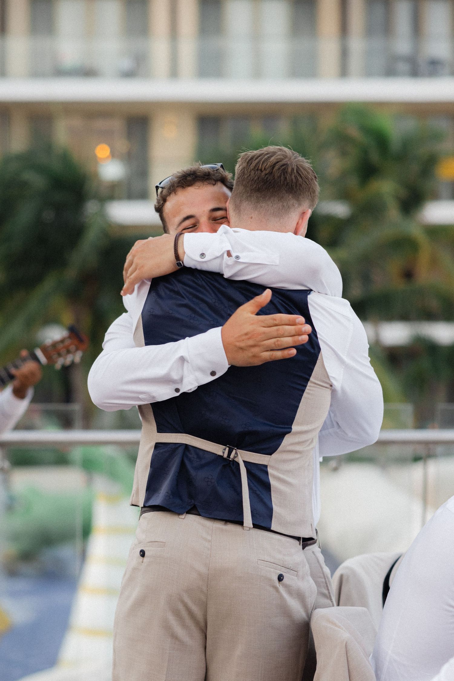 Groomsmen in formal attire sharing heartfelt hugs during wedding celebration.