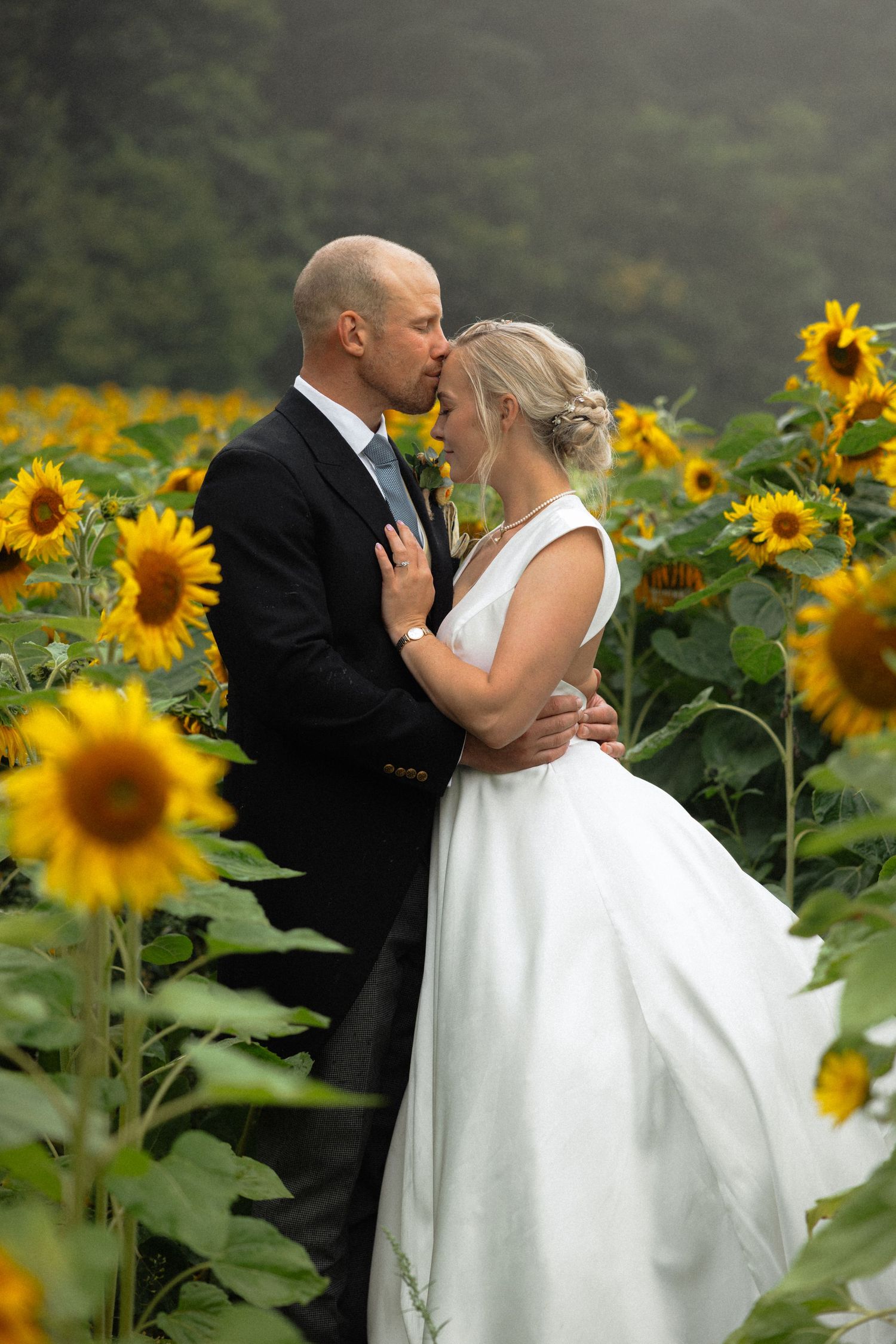 Romantic wedding portraits in sunflower field with flowing white dress.