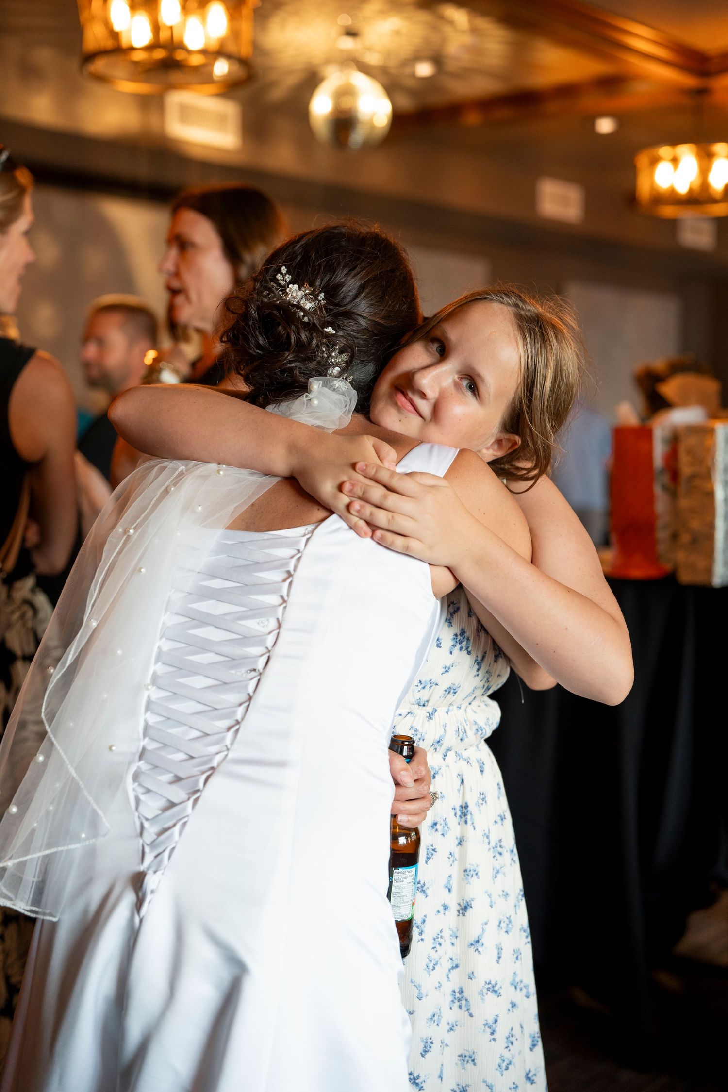 Wedding celebration moment captured in warm indoor lighting with elegant white dress details.