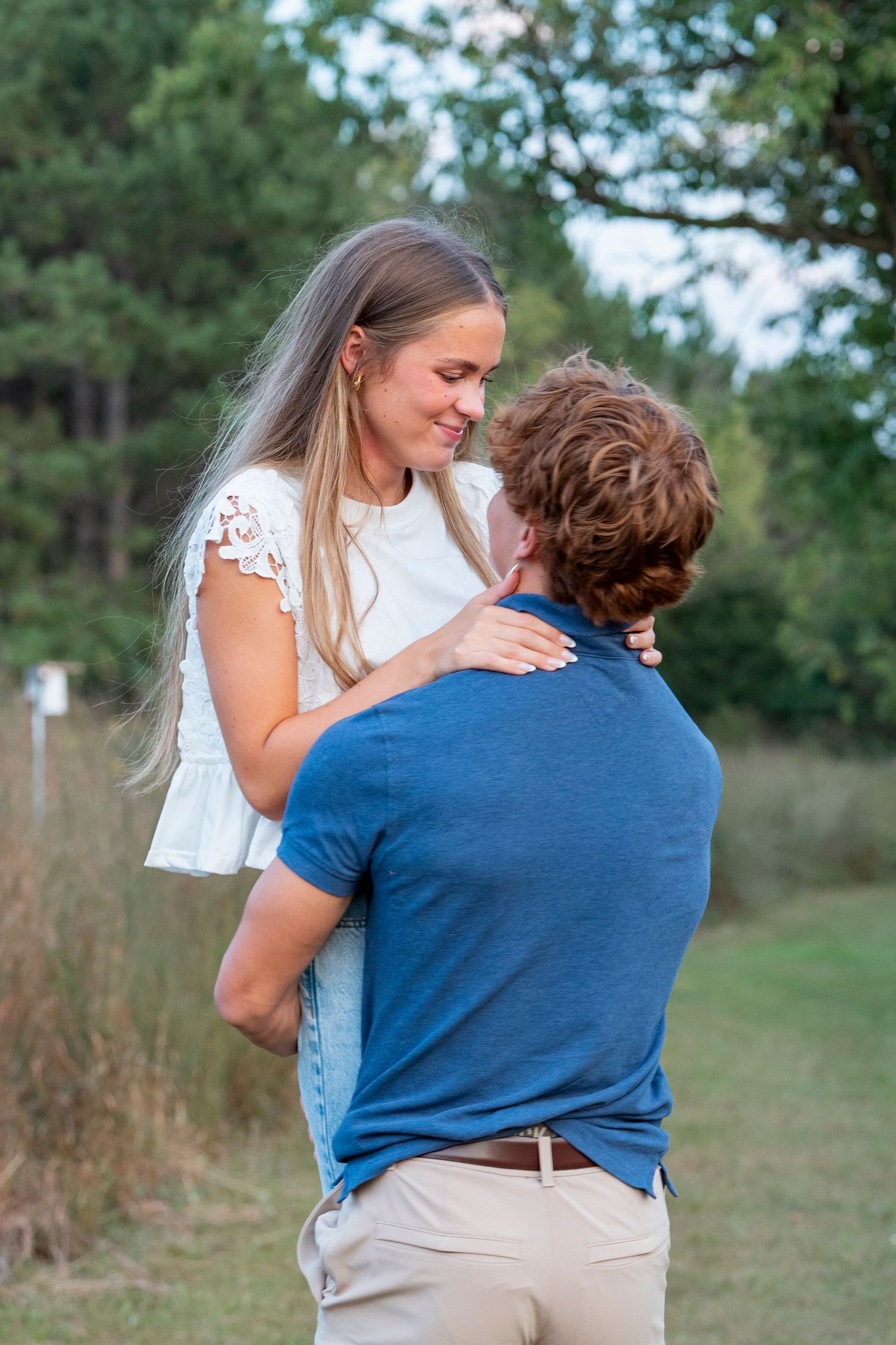 A couple shares a moment during an outdoor photoshoot near a field.