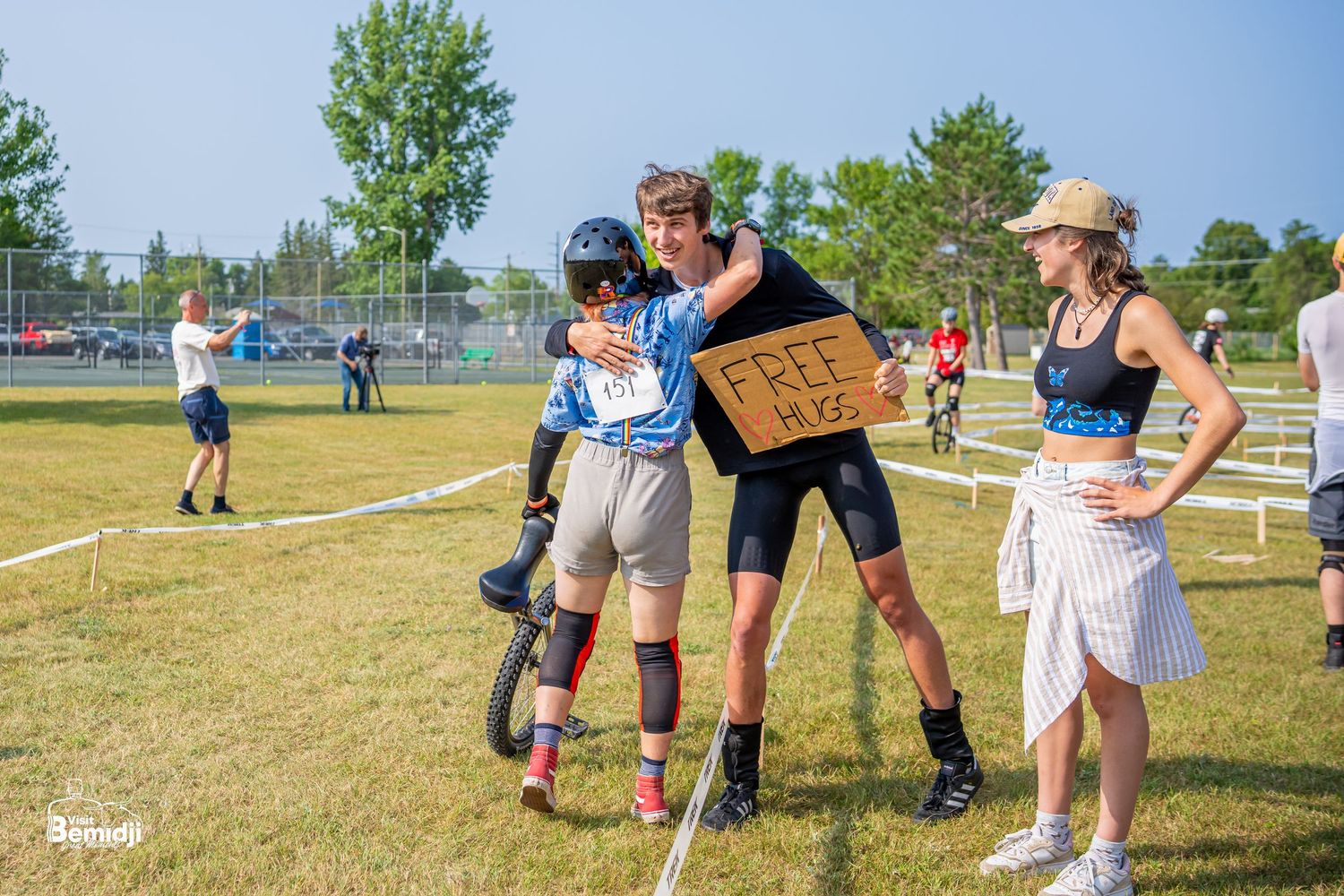 Spectators and participants gathering on a grassy field during an outdoor cycling event.
