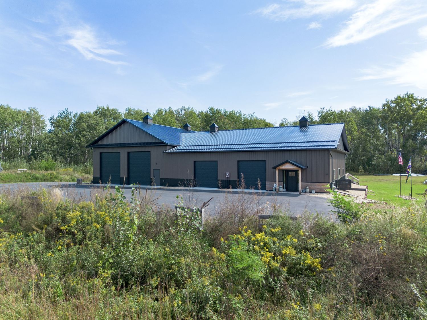 Panoramic view of commercial buildings with blue metal roofs surrounded by natural grassland.