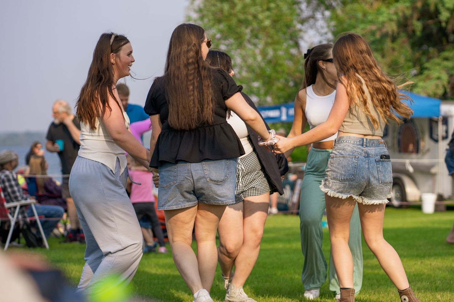 Group of people dancing outdoors on grass during a summer event.