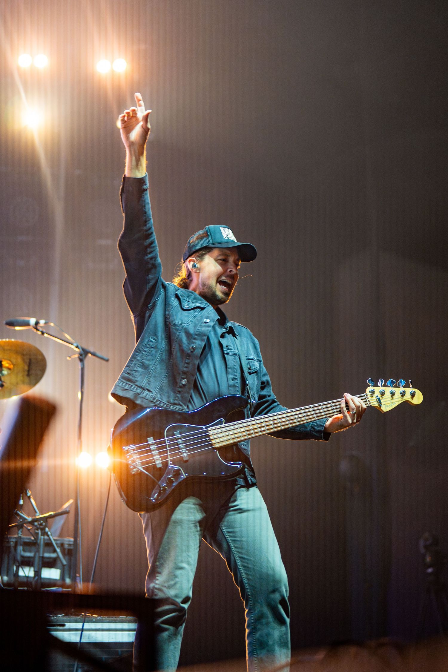 Bass guitarist in blue denim outfit performing energetically on concert stage.